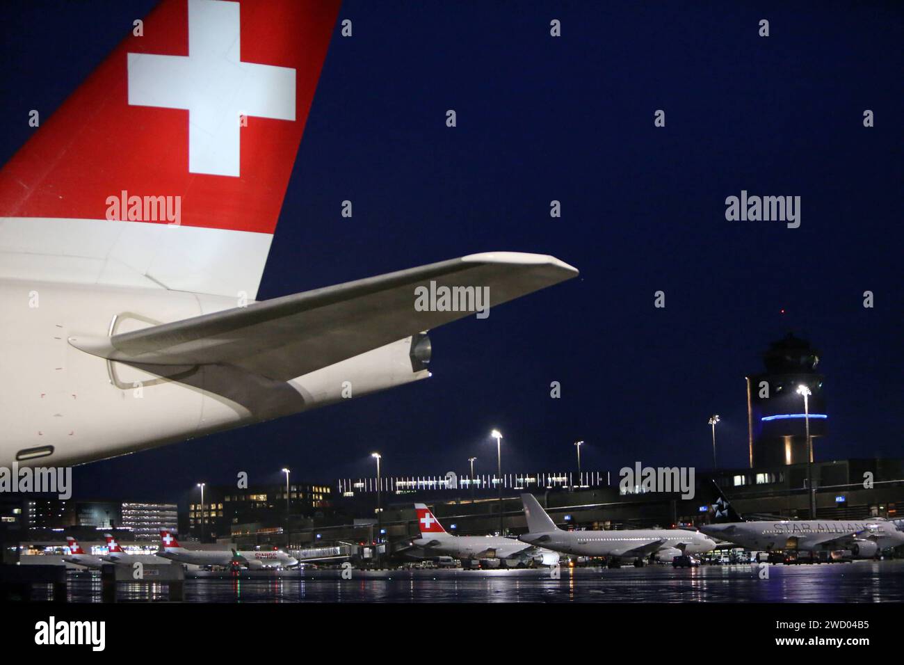 Flugzeuge auf dem Flughafen Zürich Kloten bei Nacht und Regenwetter. Im Vordergrund das