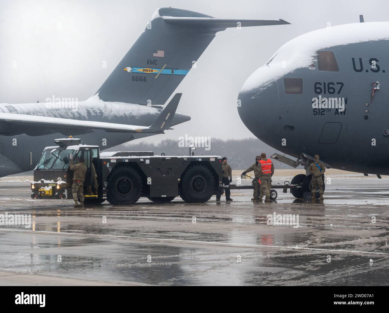 Die Betreuer bereiten am 16. Januar 2024 ein C-17 Globemaster III Flugzeug für den Schleppdienst auf der Dover Air Force Base in Delaware vor. Die Airmen arbeiteten trotz des Zentimeter Schnee, der die Fluglinie bedeckte. (Foto der U.S. Air Force von Senior Airman John Rossi) Stockfoto