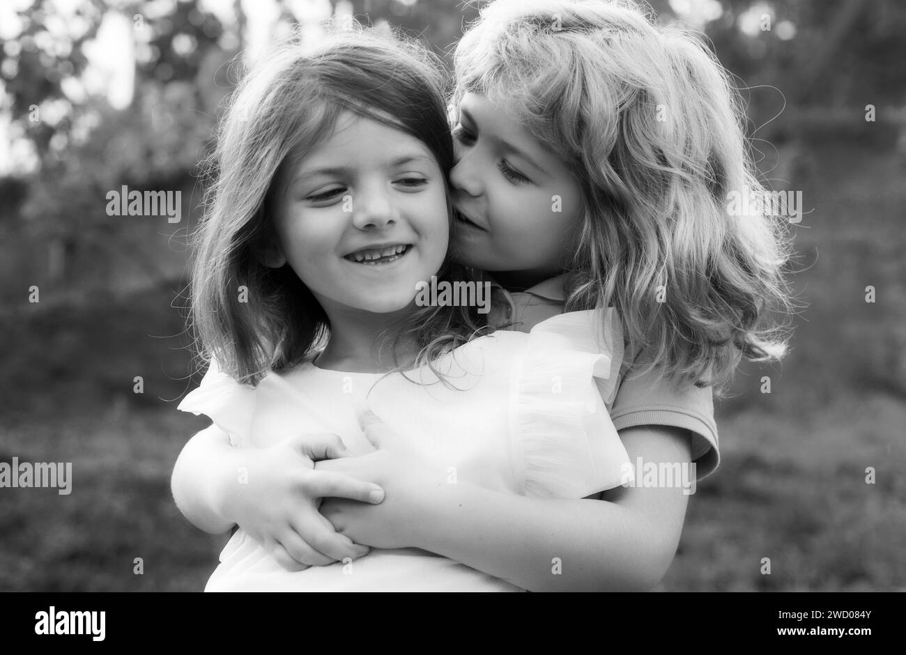 Kleiner Junge und Mädchen besten Freunde umarmt. Kinder küssen sich im Sommerpark mit Liebe. Glückliche Kinder verlieben sich im Freien am Sommertag, wenig Stockfoto