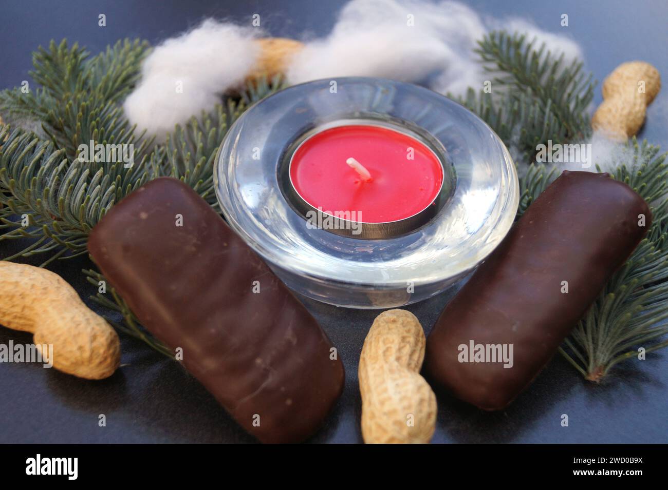 Rotes Teelicht mit Tannenzweigen, Erdnüssen und Printes Stockfoto