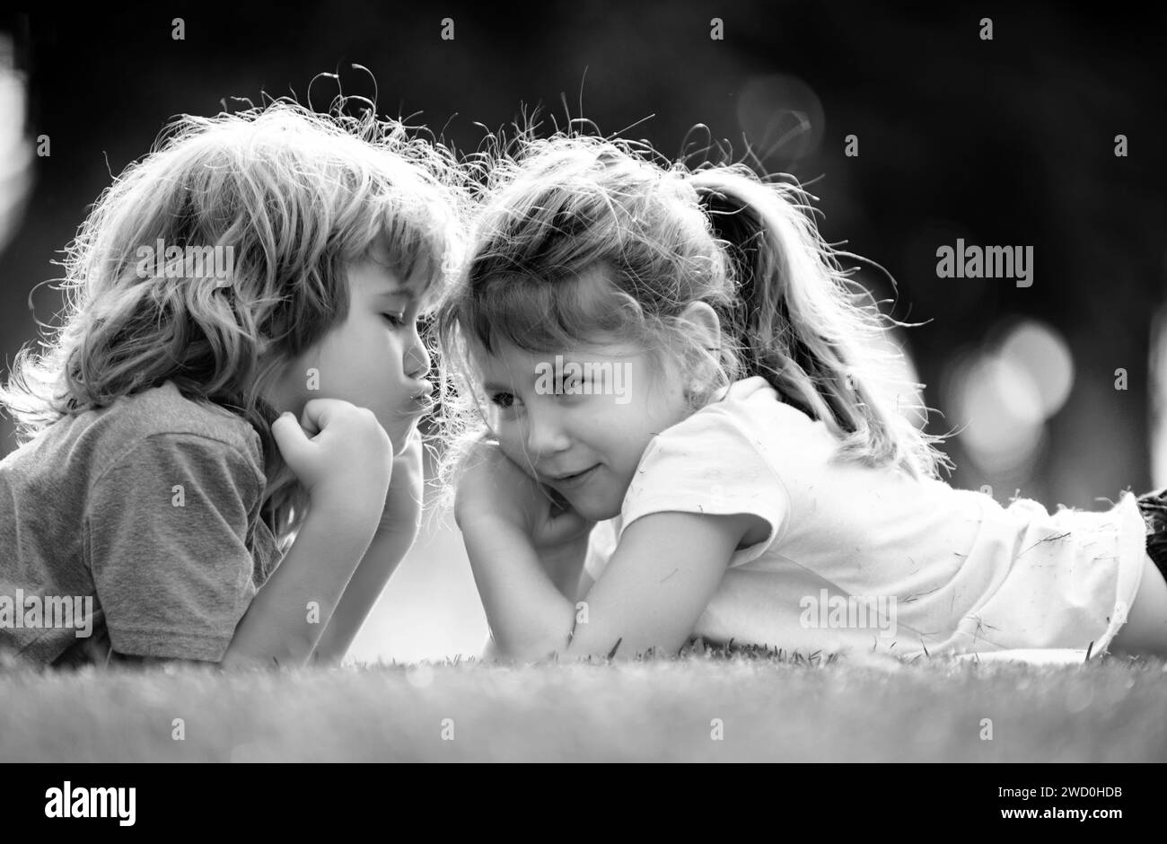 Zwei kleine Kinder umarmen und küssen sich im Sommergarten. Kinder verlieben sich. Freundschaft und Kindheit. Kinder auf Pirnic. Schüchternes Mädchen. Stockfoto