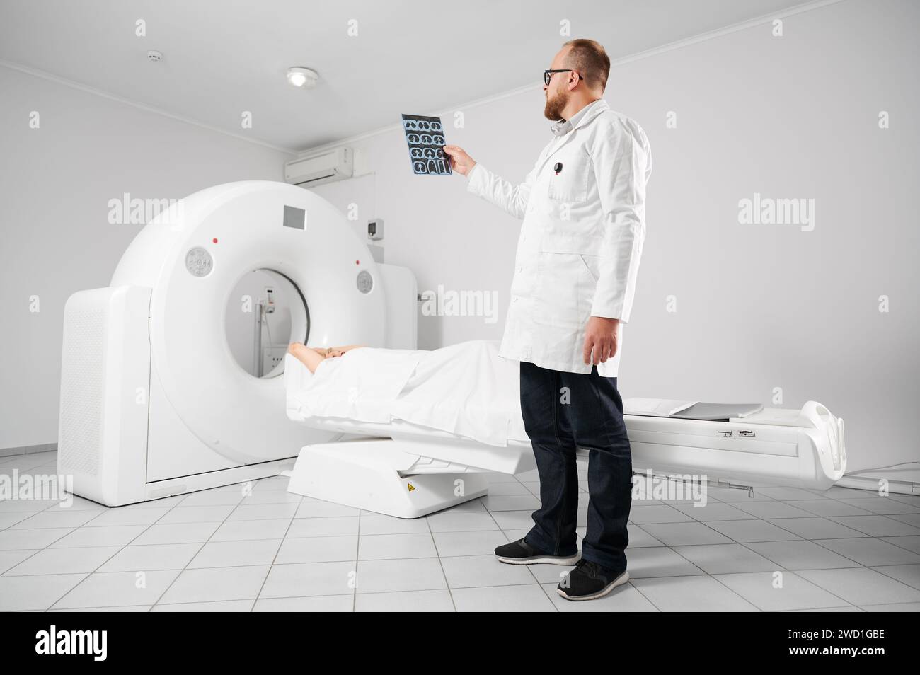 Medizinische Computertomographie oder MRT-Scanner. Arzthaltung und Untersuchungsergebnisse der MRT. Patientin, die auf dem CT-Scan-Bett liegt. Konzept von Medizin, Gesundheitswesen und moderner Diagnostik. Stockfoto