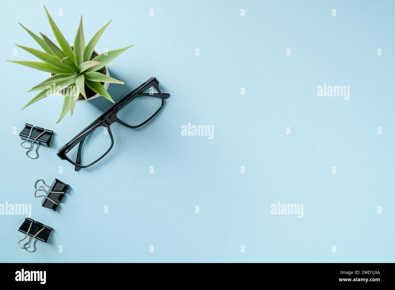 Draufsicht der Brille und der schwarzen Büroklammer auf dem blauen Tisch Stockfoto