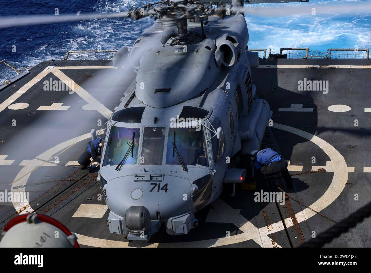 Seeleute an Bord der USS Wayne E. Meyer setzen Keile und Ketten auf einen MH-60R Sea Hawk Hubschrauber. Stockfoto