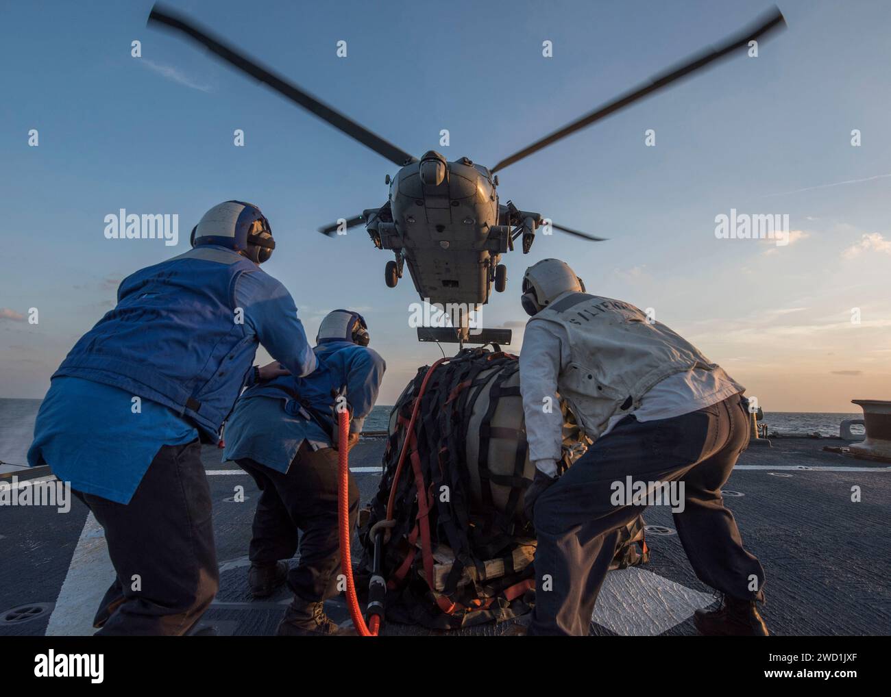 Seeleute an Bord der USS Mahan bereiten sich darauf vor, während einer vertikalen Auffüllung Fracht an einem Hubschrauber anzubringen. Stockfoto
