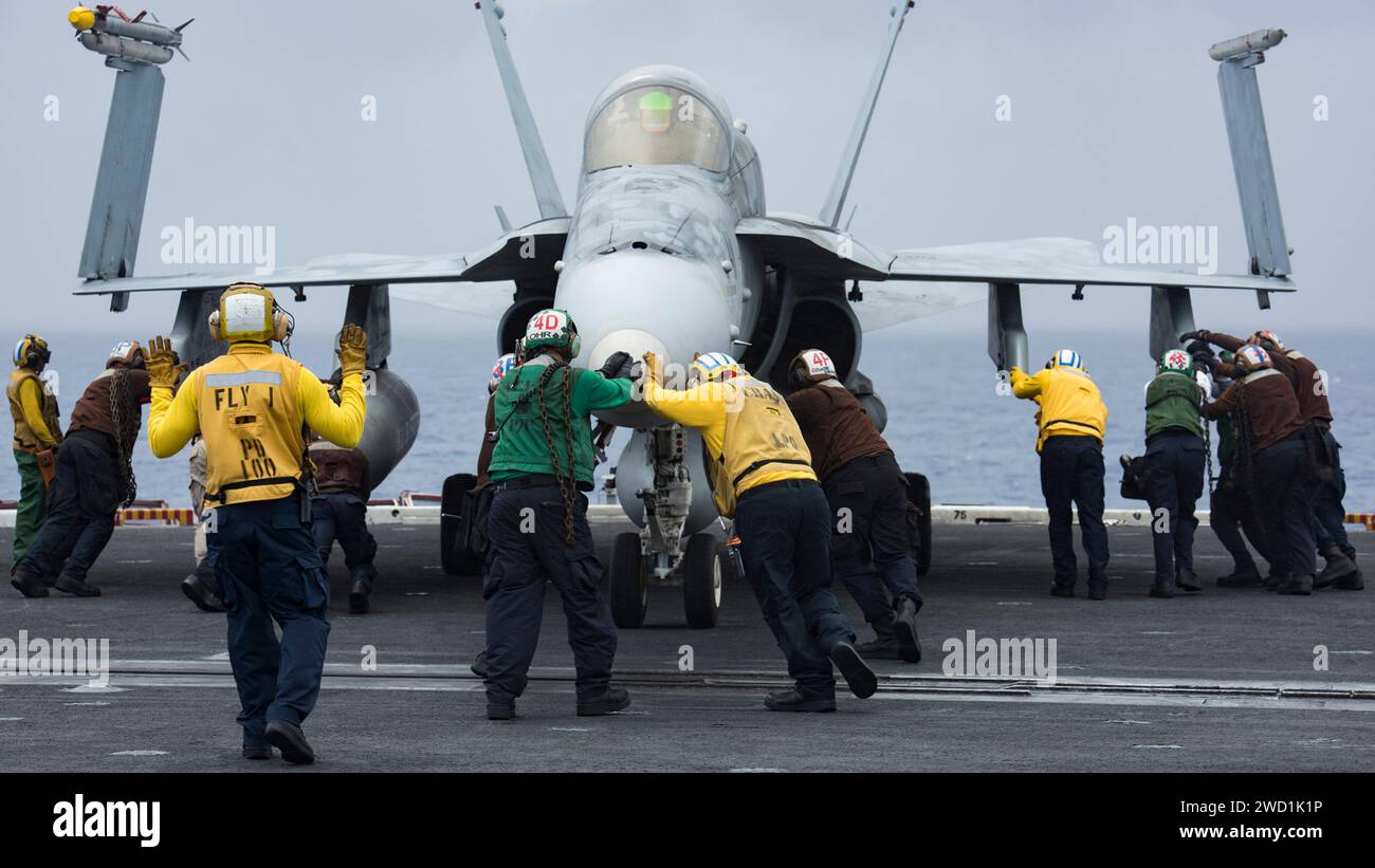 Die Matrosen schieben eine F/A-18F Super Hornet an Bord des Flugzeugträgers USS Carl Vinson zurück. Stockfoto
