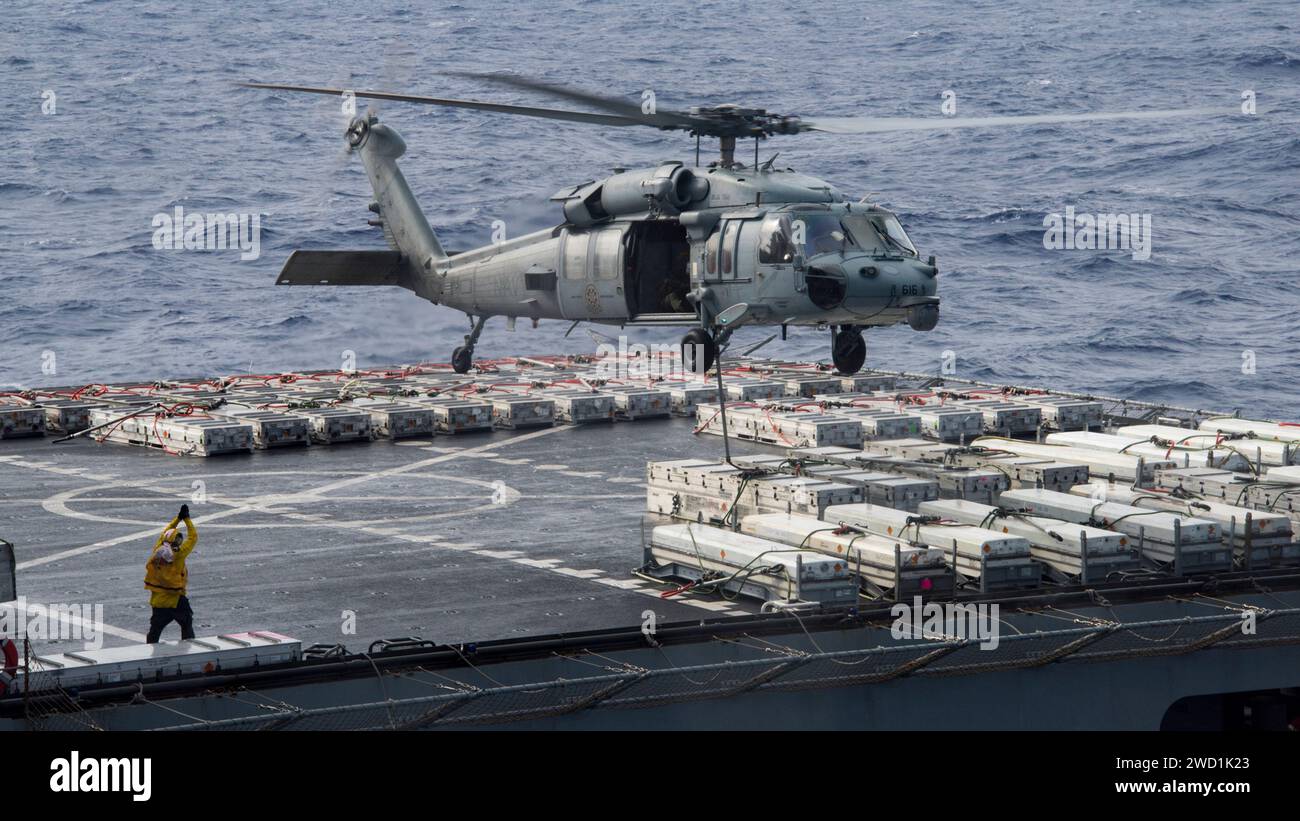 Hubschrauber, der eine vertikale Auffüllung auf See mit einem Schiff der U.S. Navy durchführt. Stockfoto