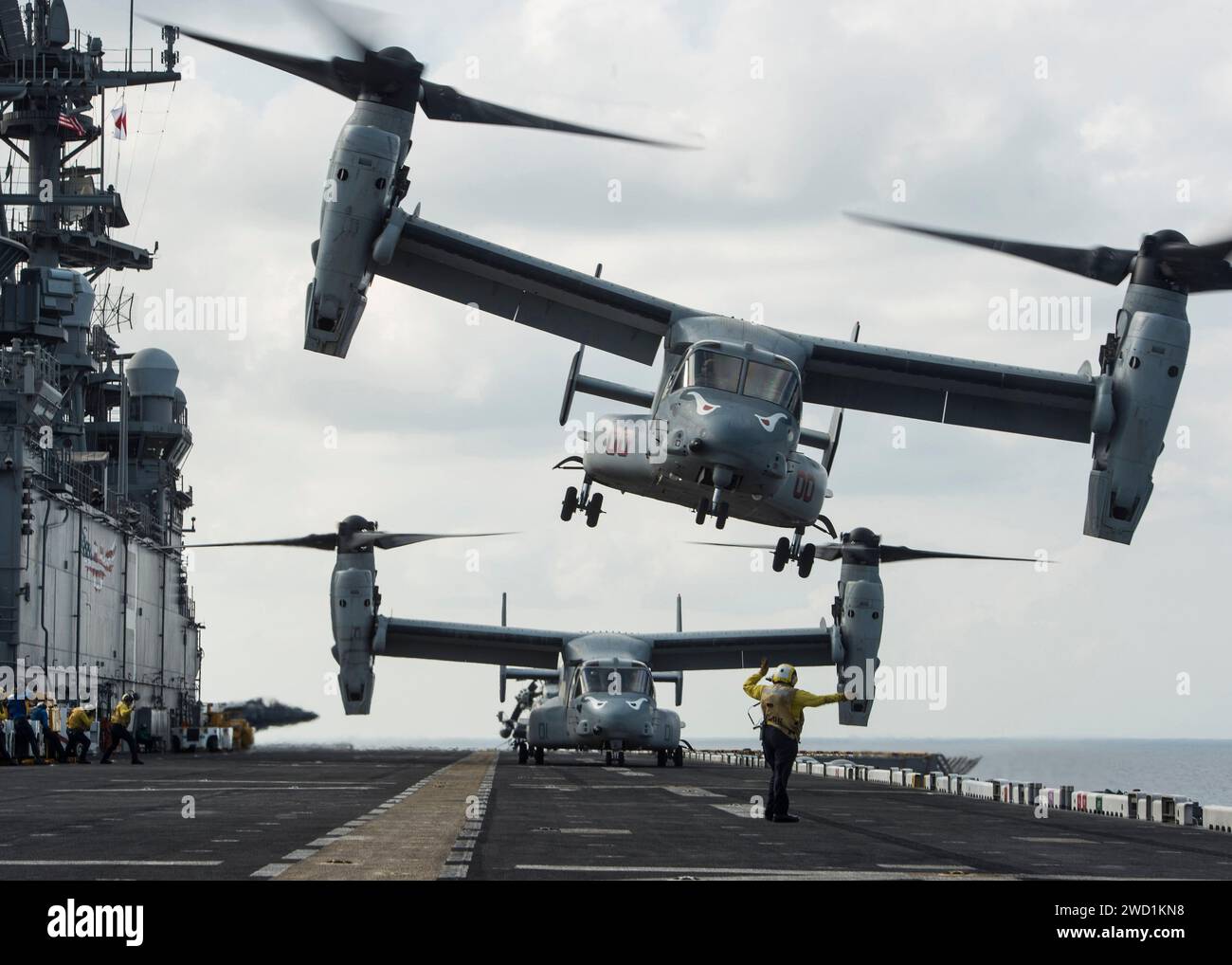 Boatswain's Mate signalisiert einem MV-22B Osprey den Start von der USS Makin Island. Stockfoto