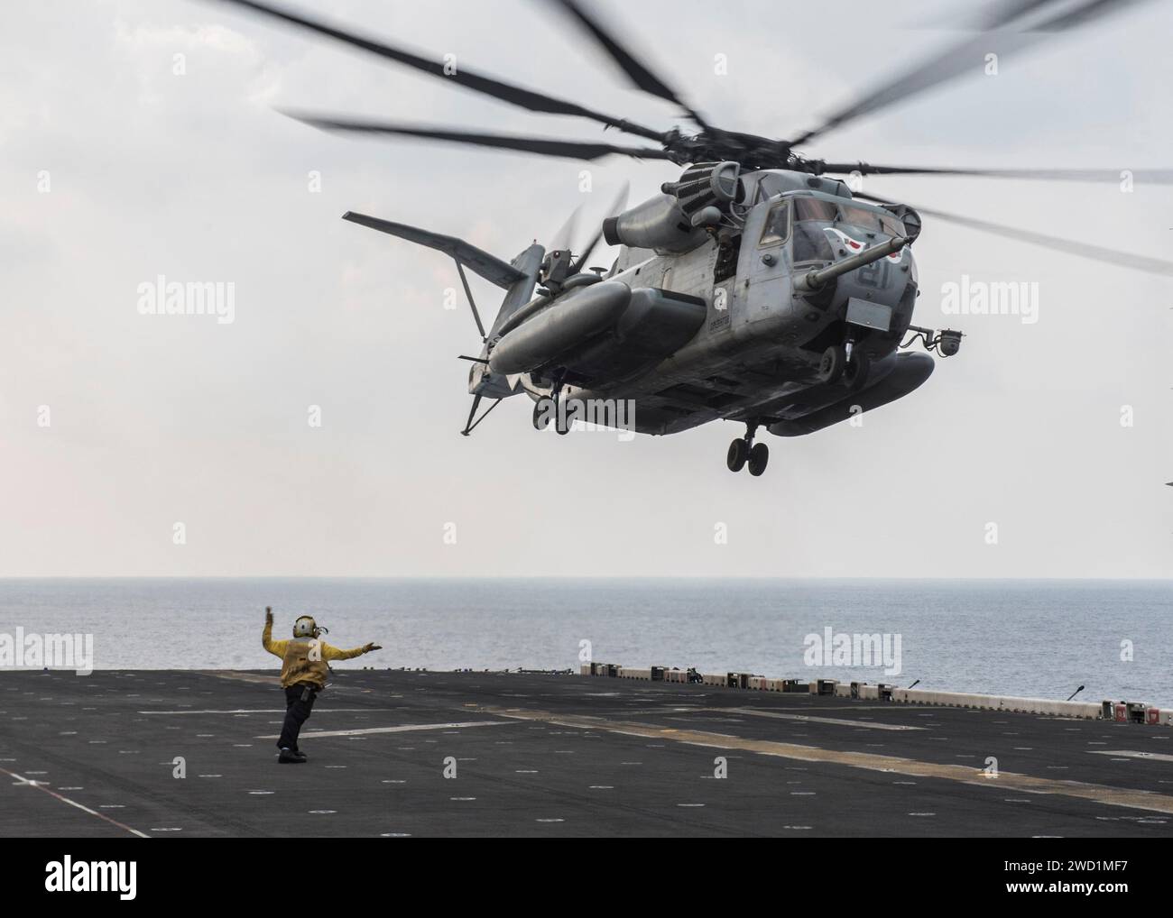 Die Boatswain's Mate signalisiert, dass ein CH-53E Super Hengst von der USS Makin Island startet. Stockfoto