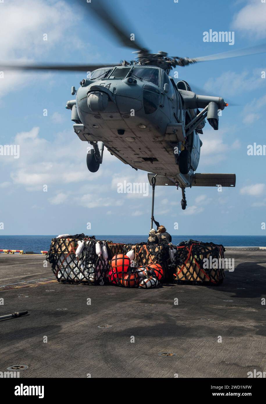 Die Marines befestigen Paletten mit Vorräten an einem MH-60S Seahawk Helikopter während einer vertikalen Auffüllung. Stockfoto