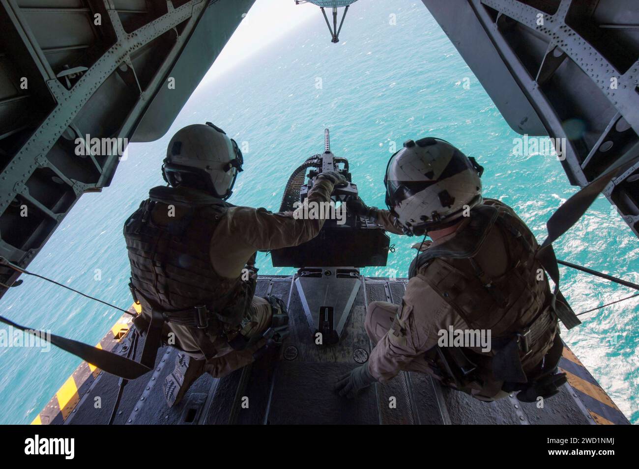 Seeleute, die ein Maschinengewehr Kaliber 50 auf dem Rücken eines MH-53E Sea Dragon besetzen. Stockfoto