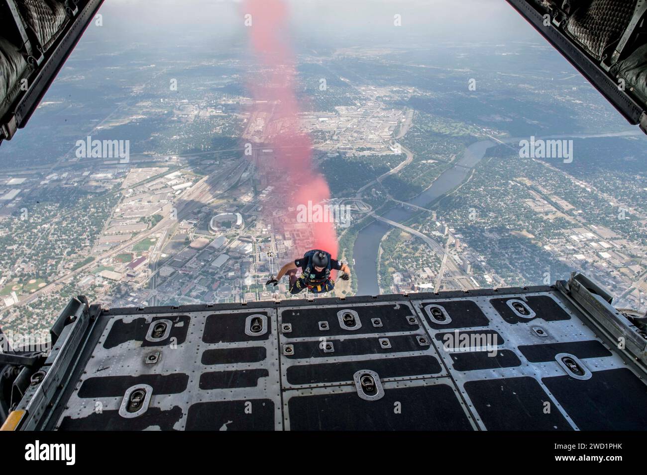 Ein Mitglied des Fallschirmdemonstrationsteams der US Navy spürt Rauch auf, während er aus einem C-130 Hercules springt. Stockfoto Ein Mitglied des Fallschirmdemonstrationsteams der US Navy spürt Rauch auf, während er aus einem C-130 Hercules springt. Stockfoto