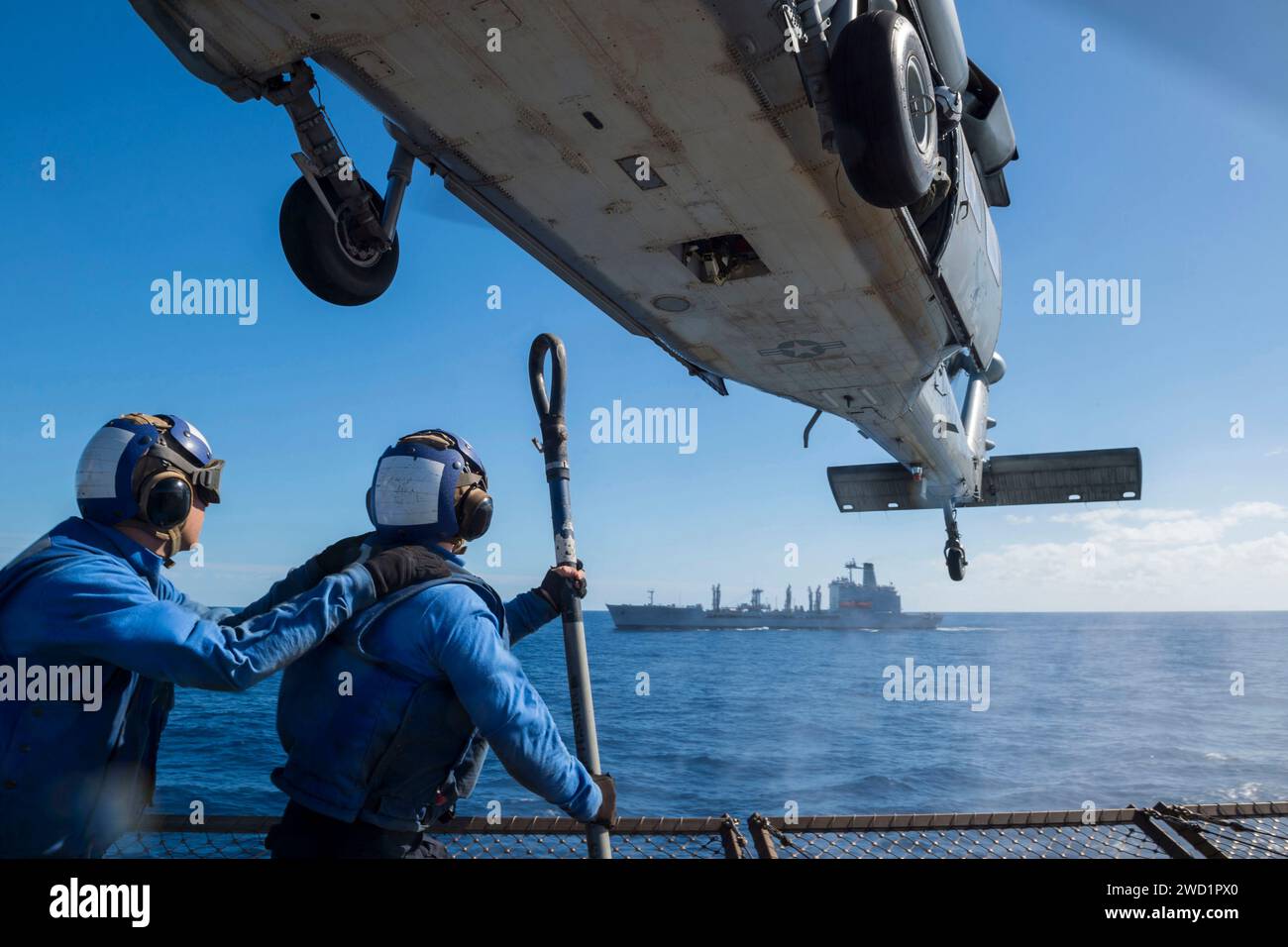 Die Flieger bereiten sich darauf vor, Frachtpaletten an einem MH-60S Sea Hawk Hubschrauber anzubringen. Stockfoto