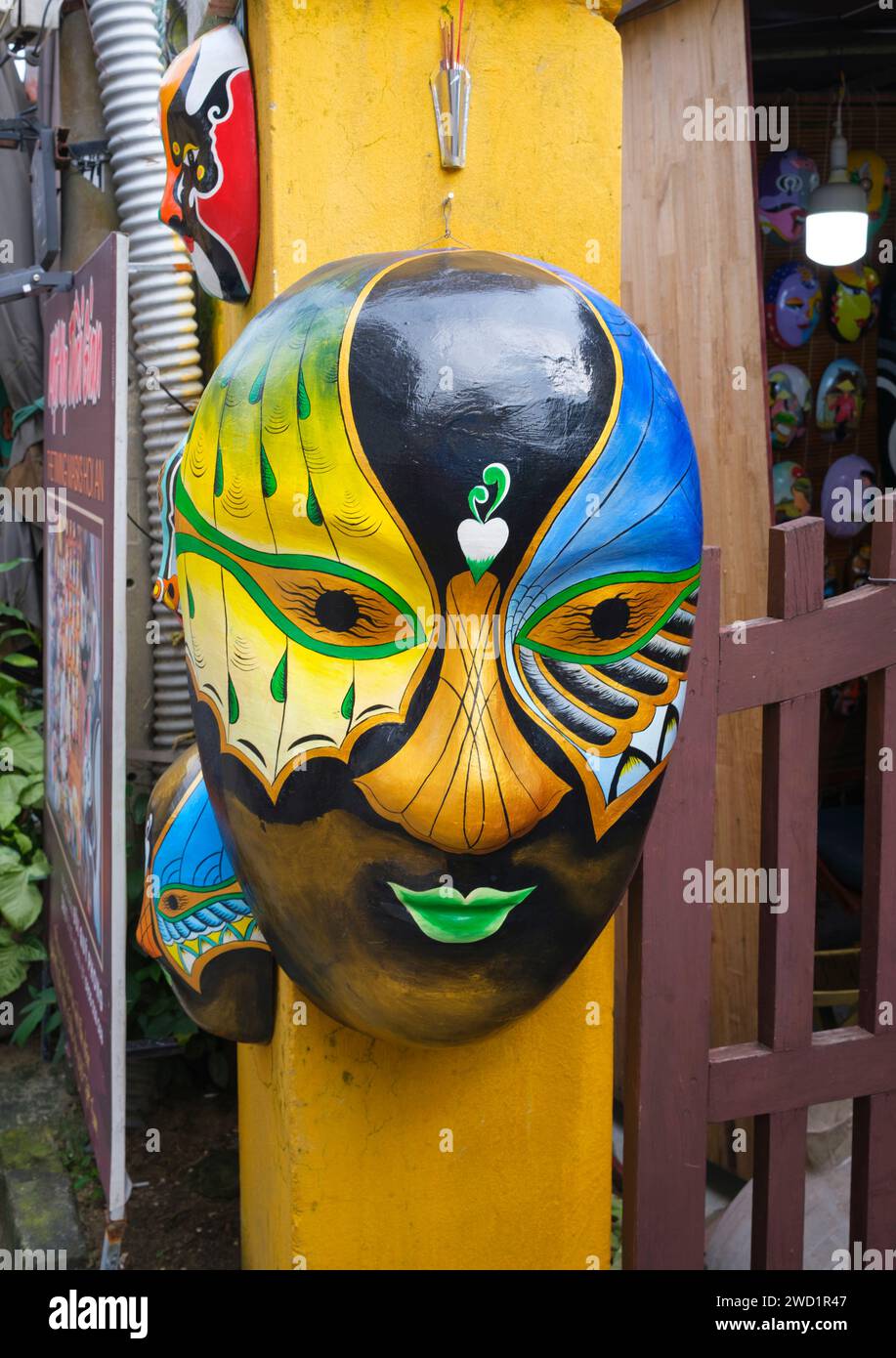 Vietnam: Eine farbenfrohe Maske auf dem vorderen Torpfosten der Timing Mask, einer Firma, die auf handgefertigte Masken spezialisiert ist, Le Loi, Altstadt, Hoi an. Die kleine, aber historische Stadt Hoi an liegt am Fluss Thu Bon 30 km südlich von Danang. Während der Zeit der Nguyen Lords (1558–1777) und sogar unter den ersten Nguyen-Kaisern war Hoi an – damals bekannt als Faifo – ein wichtiger Hafen, der regelmäßig von Schiffen aus Europa und dem ganzen Osten besucht wurde. Stockfoto