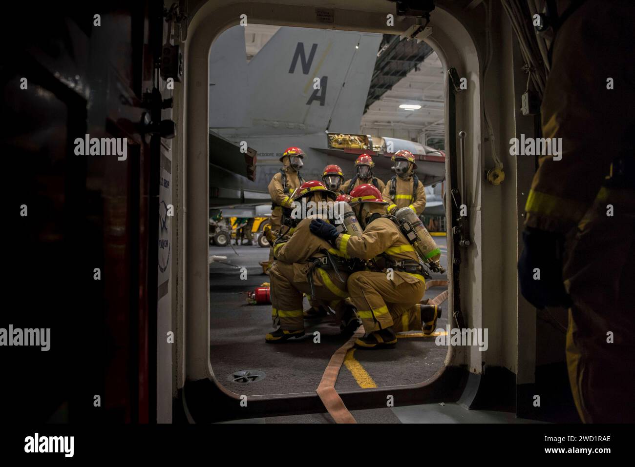 Seeleute führen während einer allgemeinen Übung in der Hangarbucht der USS Theodore Roosevelt Feuerlöschübungen durch. Stockfoto
