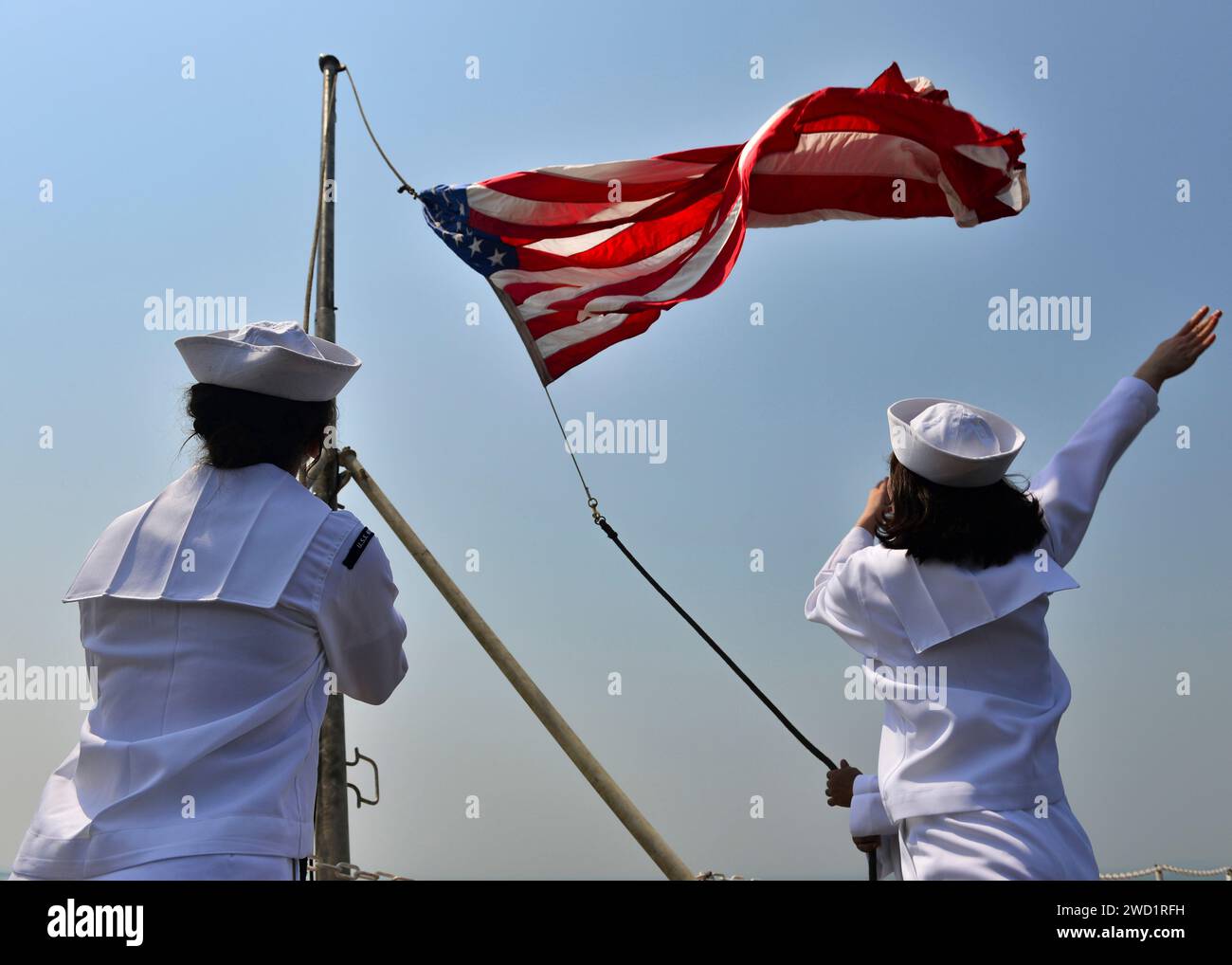 Die Matrosen heben die Fähnrich auf, während der Flugzeugträger USS Nimitz nach dem Festmachen in Bahrain die Farben wechselt. Stockfoto