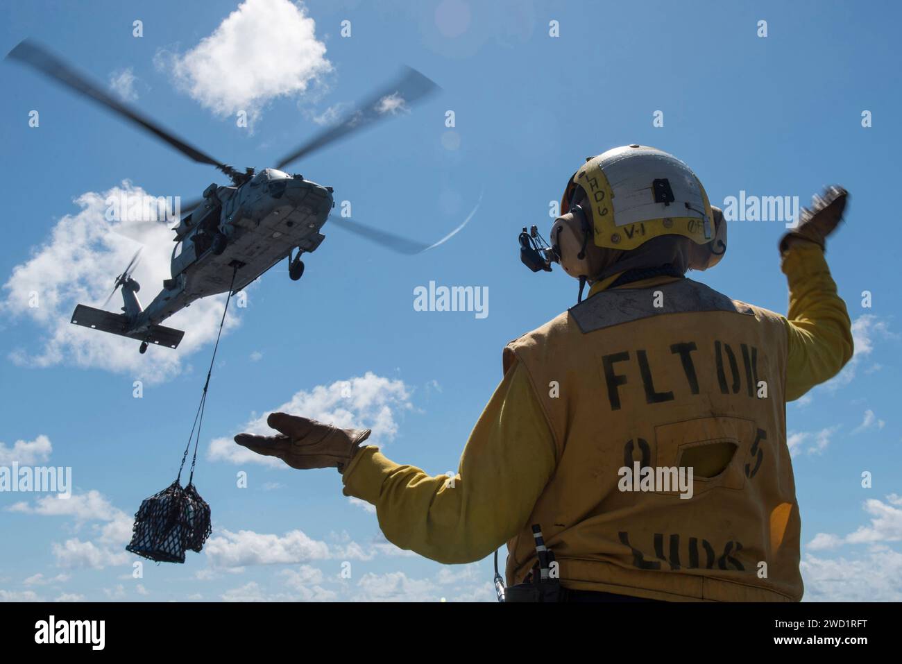 Boatswain's Mate meldet einen MH-60S Sea Hawk Hubschrauberpiloten während einer vertikalen Auffüllung. Stockfoto