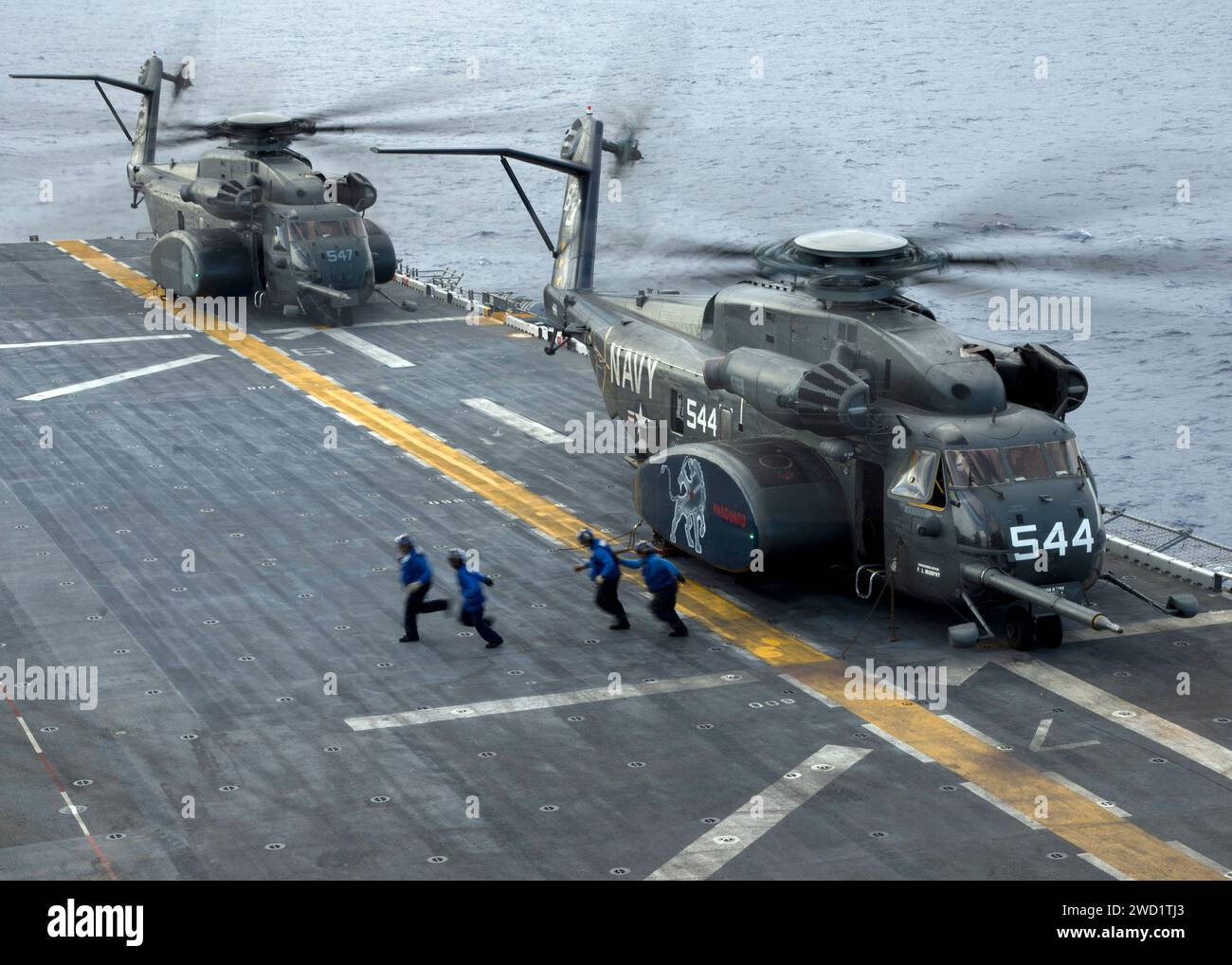 Die Matrosen laufen auf die Foul-Linie zu, nachdem sie mit zwei MH-53E Sea Dragon Helikoptern eine Keil- und Kettenentwicklung beendet haben. Stockfoto