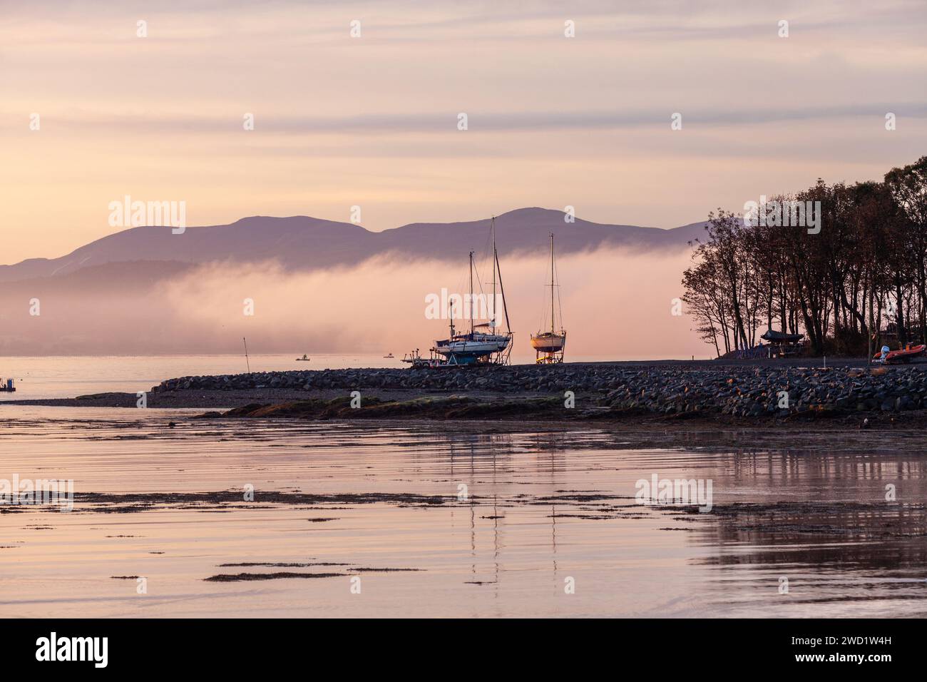 Yachten aus dem Wasser im Dalgety Bay Segelclub mit einem nebeligen Firth of Forth und Pentland Hills im Hintergrund Stockfoto