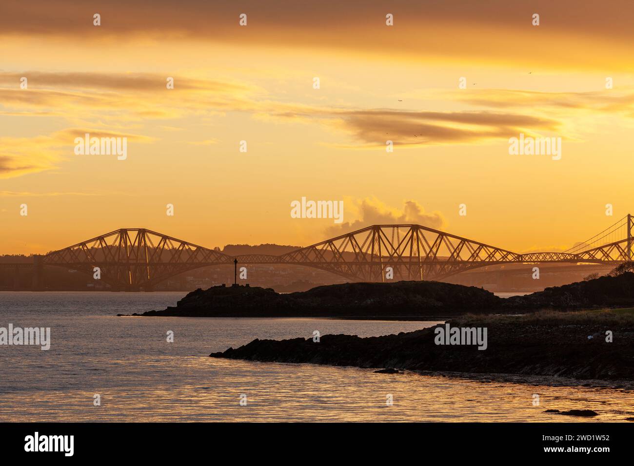 Ein wunderschöner Sonnenuntergang über der Forth Bridge mit Downing Point im Vordergrund, Dalgety Bay, Fife. Stockfoto