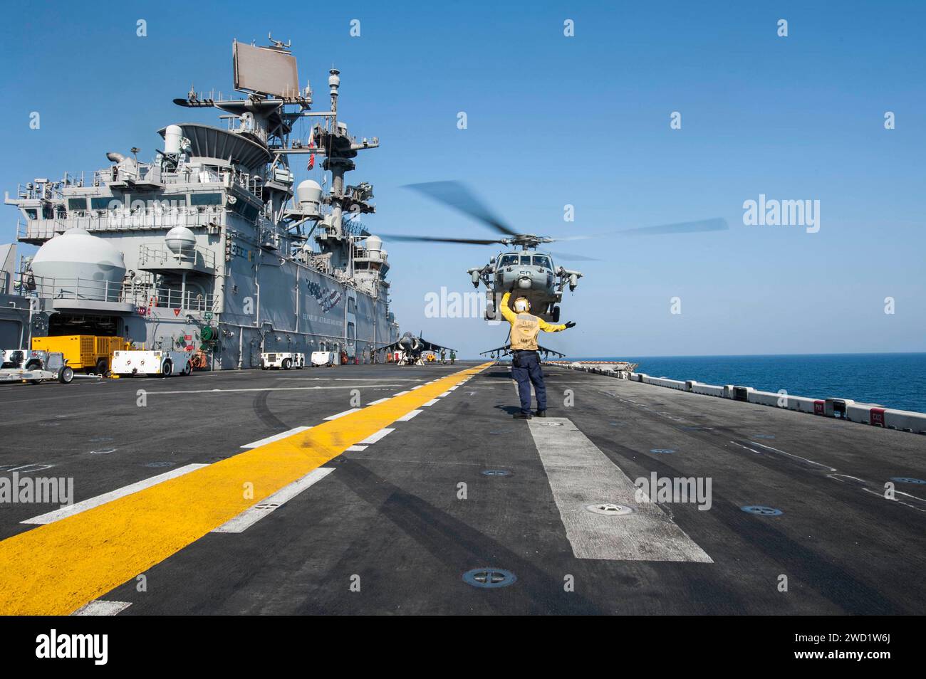 Die Fluggesellschaft Boatswain's Mate signalisiert einen MH-60S Sea Hawk Helikopter, der von der USS America abhebt. Stockfoto