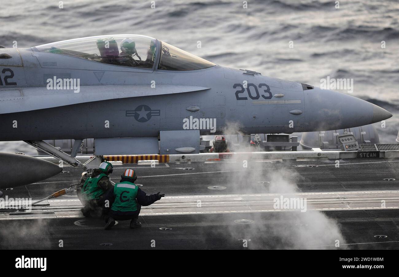 Die Matrosen führen vor dem Flug Kontrollen an einer F/A-18C Hornet auf dem Flugdeck der USS Theodore Roosvelt durch. Stockfoto
