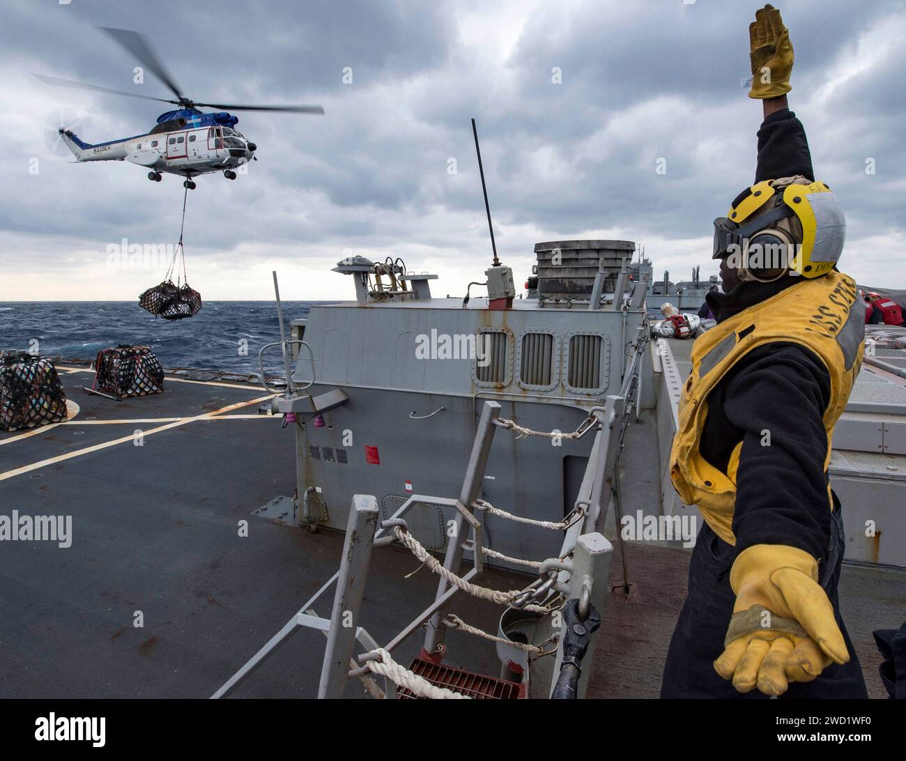 Boatswain's Mate signalisiert einen SA 330 Puma Hubschrauber während einer vertikalen Auffüllung. Stockfoto