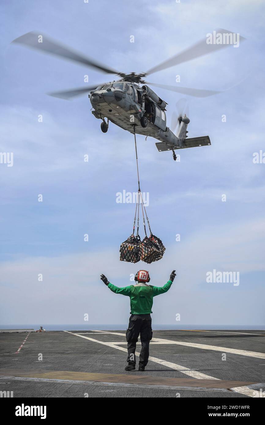Ein MH-60S Sea Hawk Helikopter transportiert Fracht zum Flugzeugträger USS Theodore Roosevelt. Stockfoto