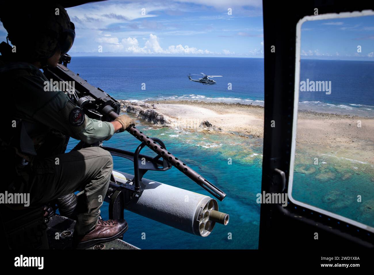 Ein U.S. Marine schaut aus der Tür eines UH-1Y Huey Hubschraubers auf eine AH-1Z Cobra. Stockfoto