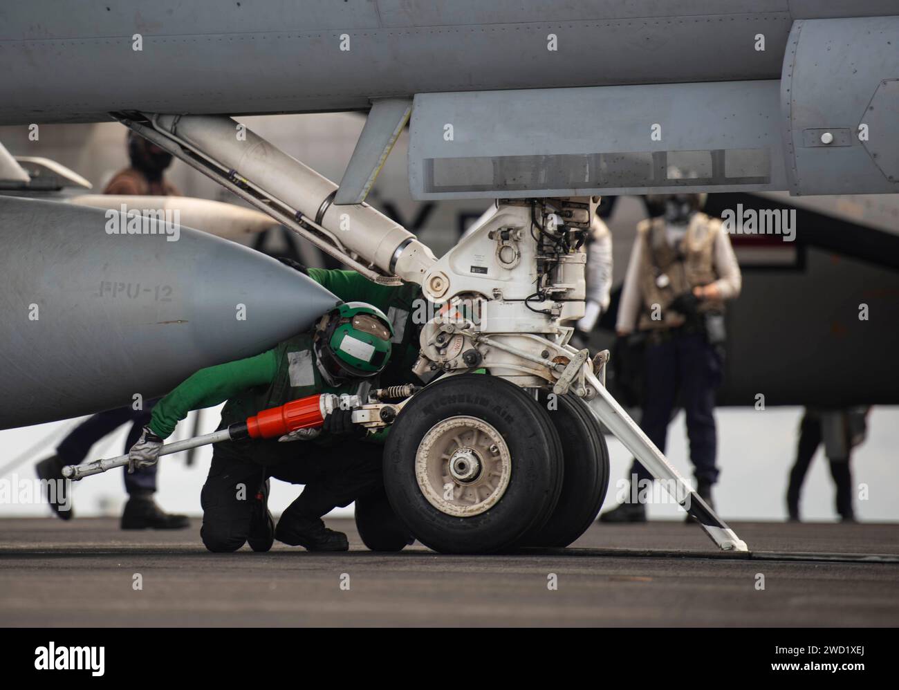Aviation Boatswain's Mate platziert einen Haltebügel an einer F/A-18E Super Hornet, während sie sich auf den Start vorbereitet. Stockfoto