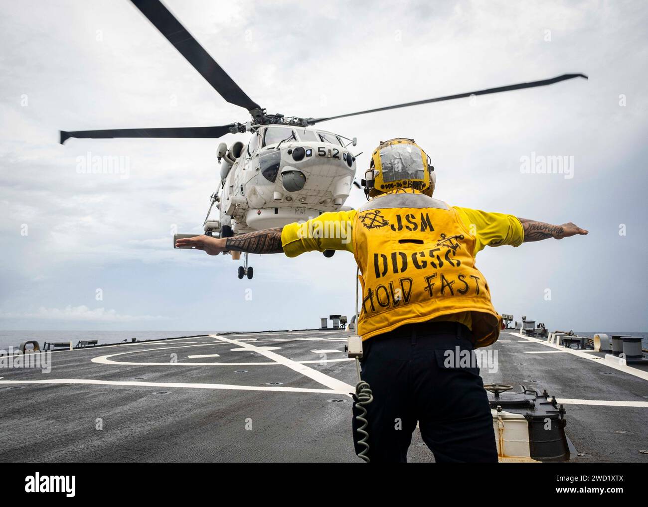 Boatswain's Mate signalisiert einem Helikopter der japanischen Seefahrtruppe SH-60, auf dem Flugdeck zu landen. Stockfoto