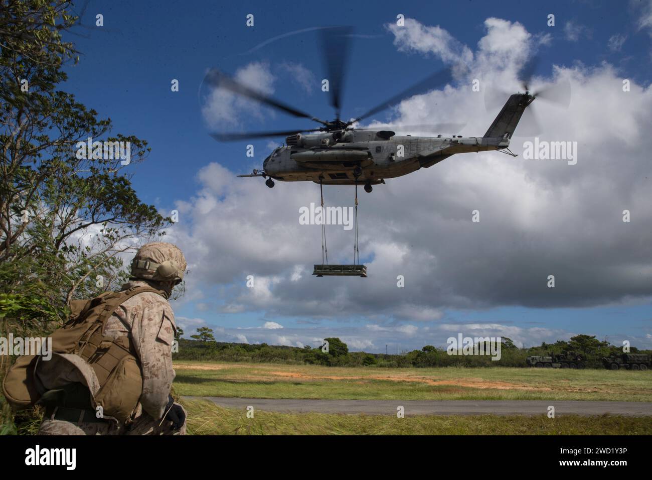 U.S. Marine beobachtet einen CH-53 Seehengst mit einem High Mobility Artillery Rocket System. Stockfoto