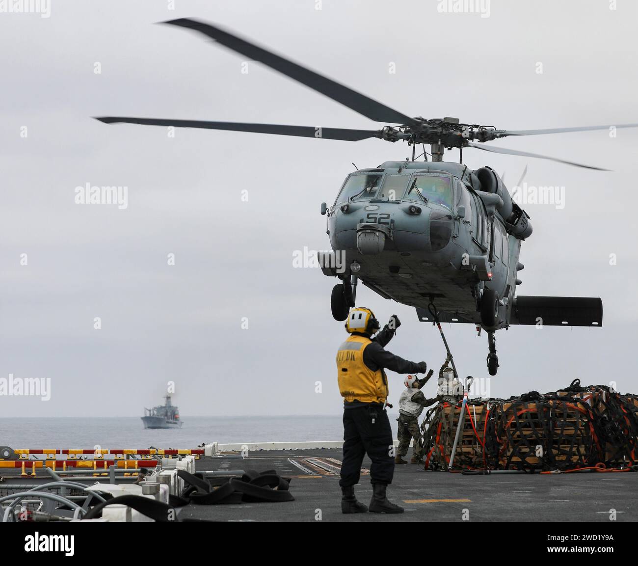 Aviation Boatswain's Mate steuert einen MH-60S Sea Hawk Hubschrauber auf dem Flugdeck der USS Makin Island. Stockfoto