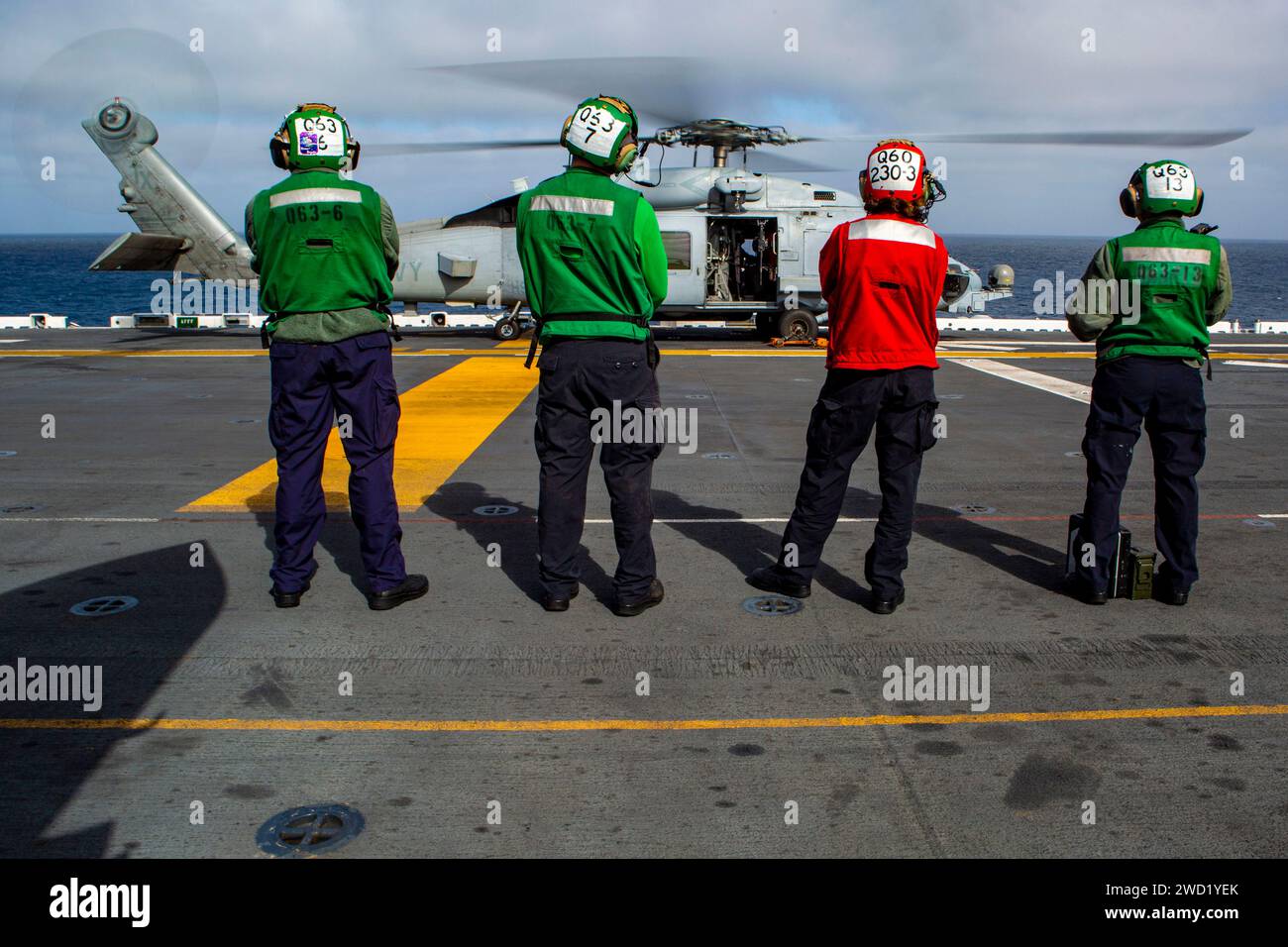Seeleute an Bord des amphibischen Angriffsschiffs USS Makin Island warten auf den Start eines MH-60R Sea Hawk Hubschraubers. Stockfoto
