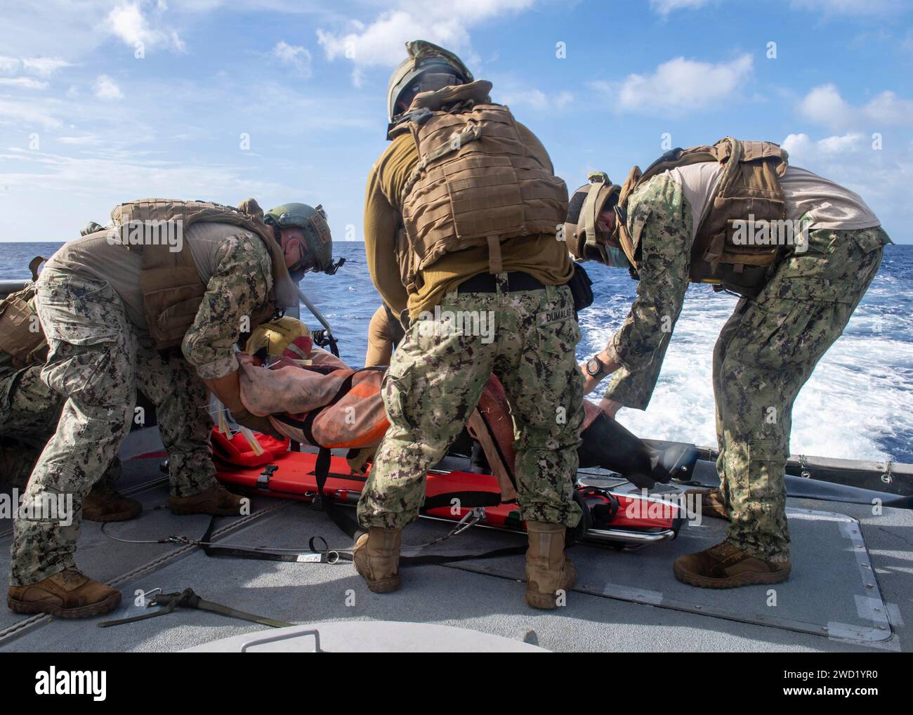 Matrosen bereiten ein simuliertes Opfer für den Hubschraubertransport auf einem Mark VI Patrouillenboot vor. Stockfoto