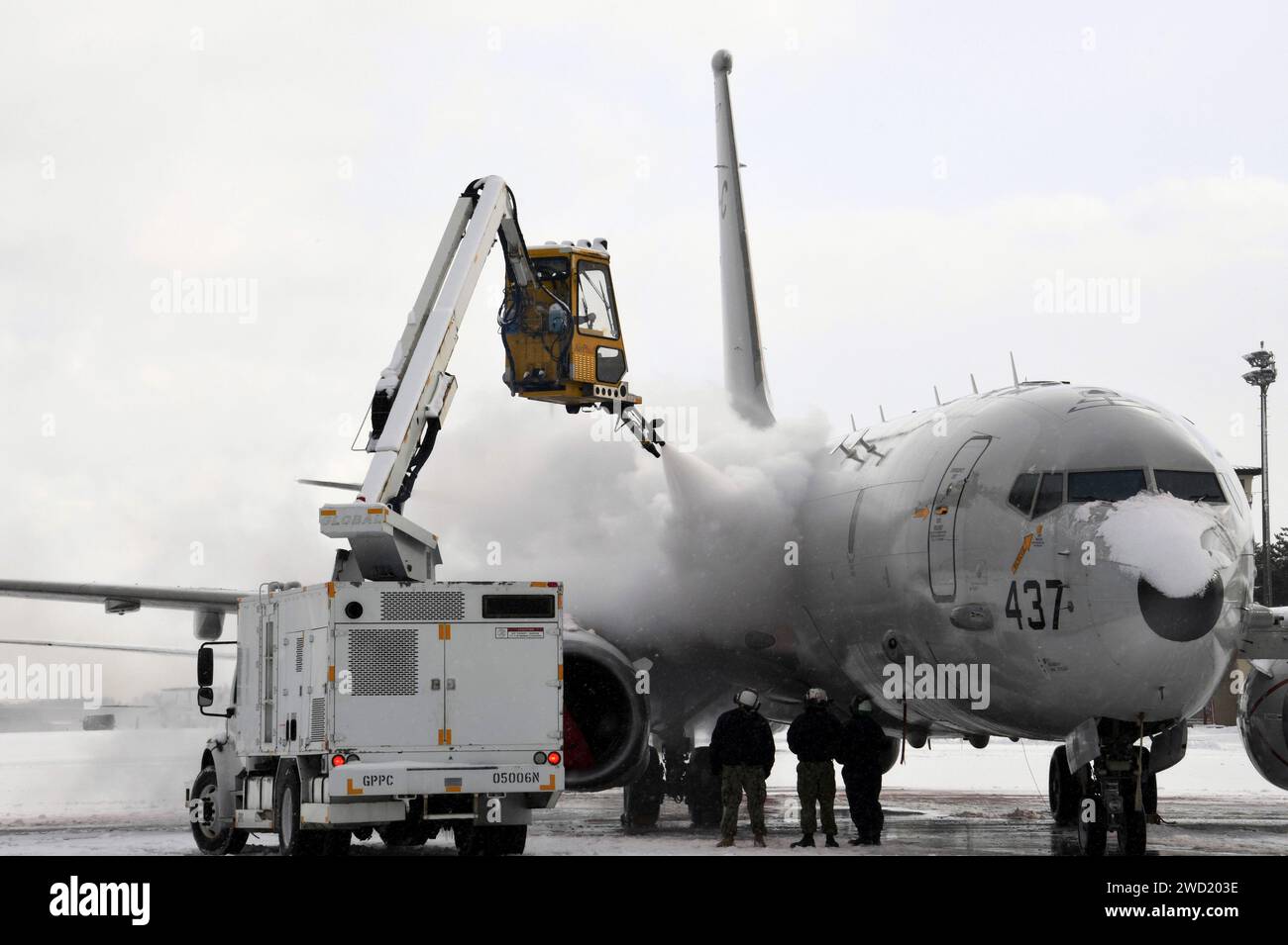 Aviation Machinist's Mate betreibt einen Enteisungswagen, um Schnee und Eis von einem P-8A Poseidon zu entfernen. Stockfoto