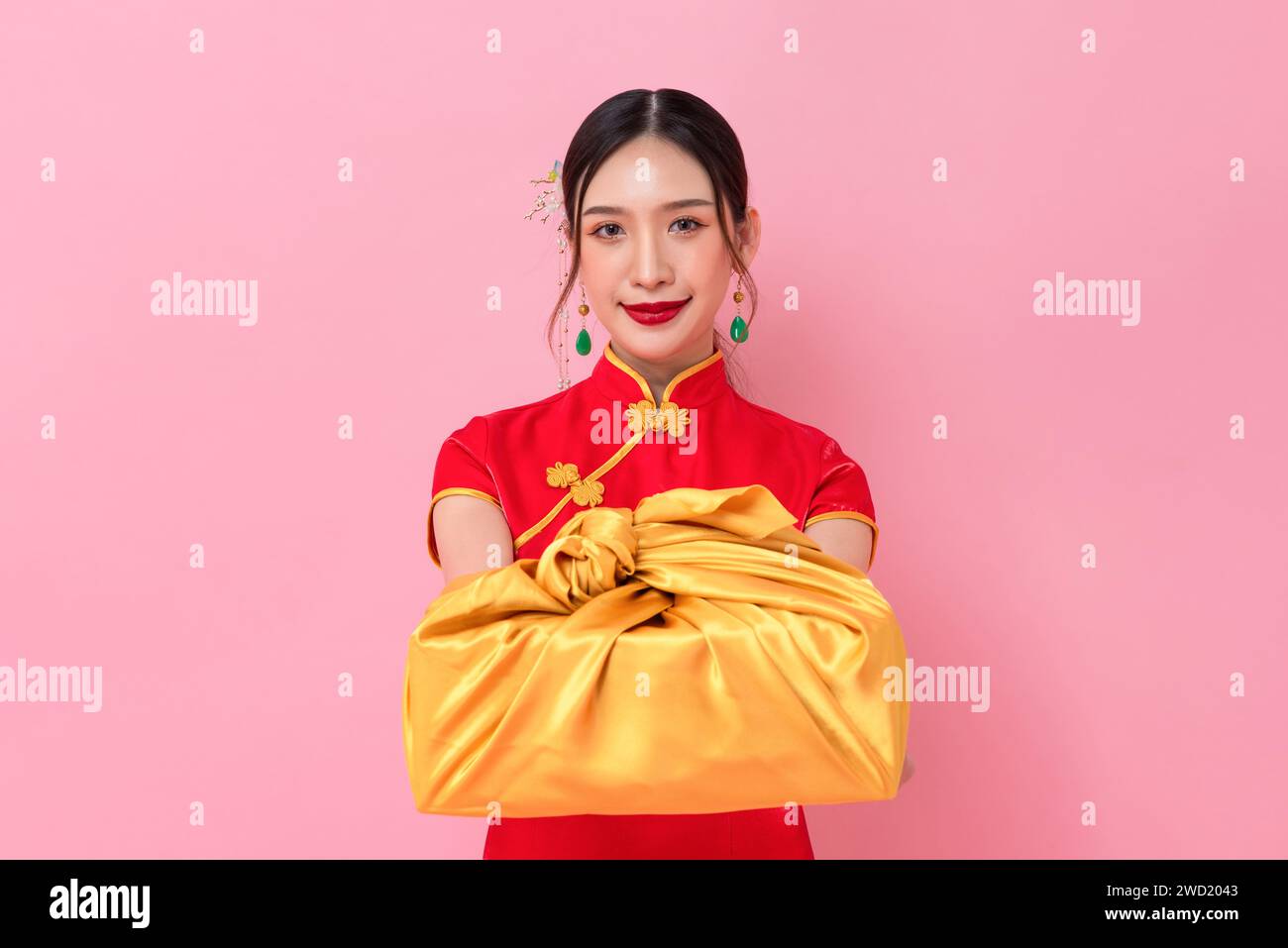 Chinesisches Neujahrsprofil der eleganten asiatischen Frau im traditionellen Cheongsam Kleid, das goldene Geschenkbox in rosa Hintergrund gibt Stockfoto