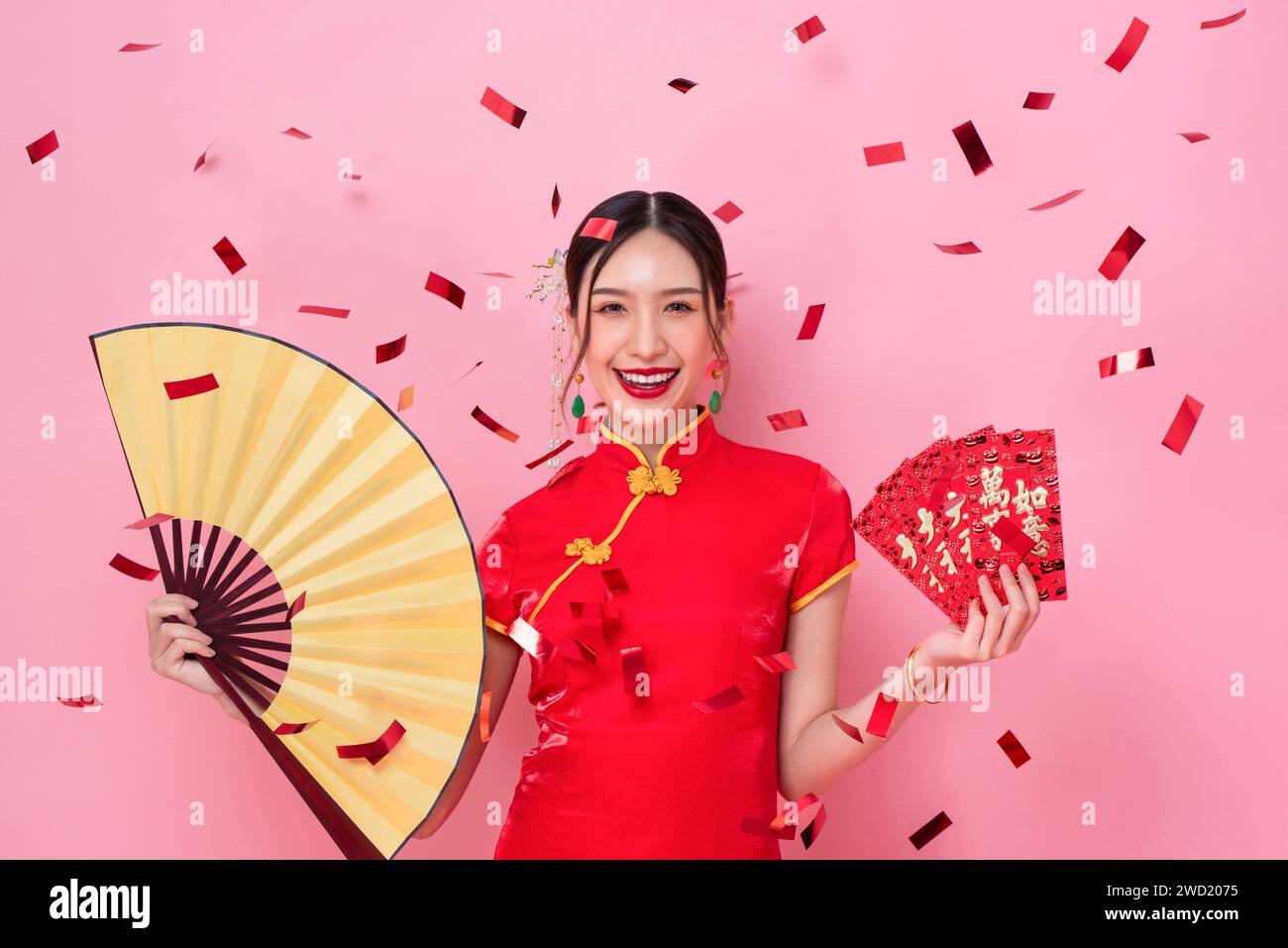 Chinesisches Neujahrsporträt einer asiatischen Frau in traditioneller Cheongsam-Kleidung auf rosa Hintergrund mit Konfetti, Fremdsprachenübersetzung als alles Stockfoto