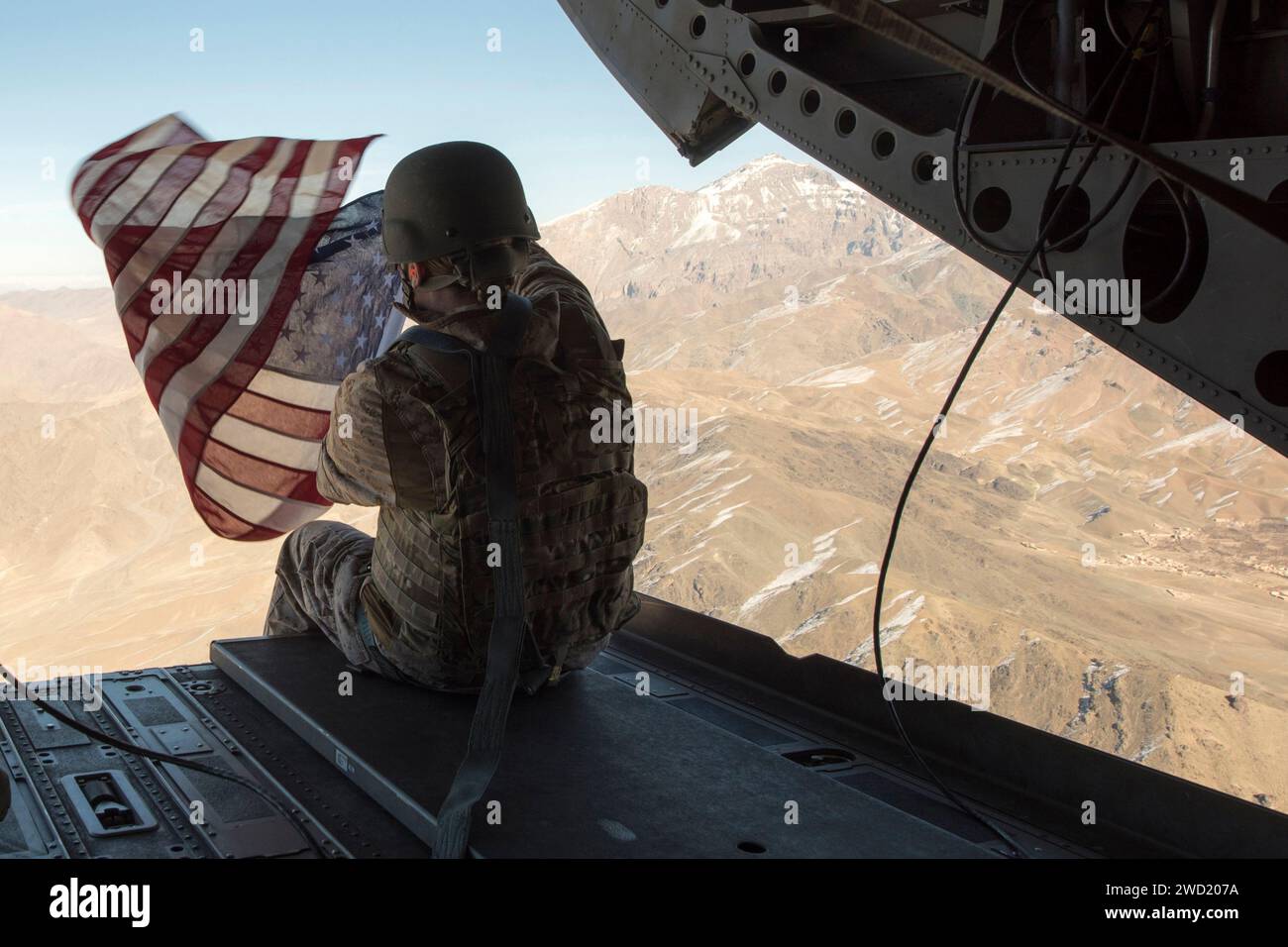 U.S. Marine hält die amerikanische Flagge auf der Rückseite eines CH-47 Chinook Hubschraubers. Stockfoto
