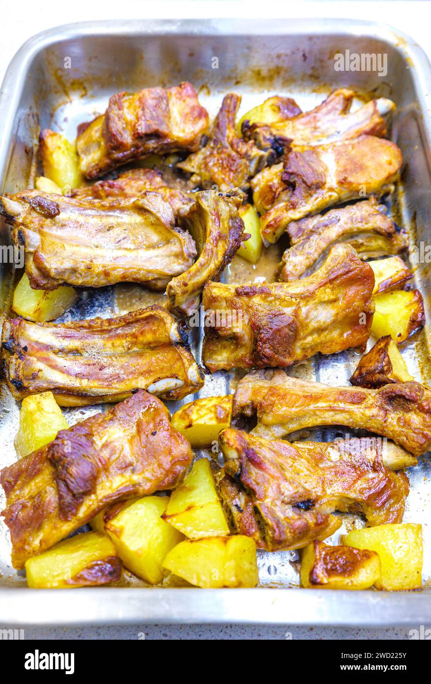 Gebackene Schweinerippchen mit Kartoffeln in einem Backblech. Stockfoto