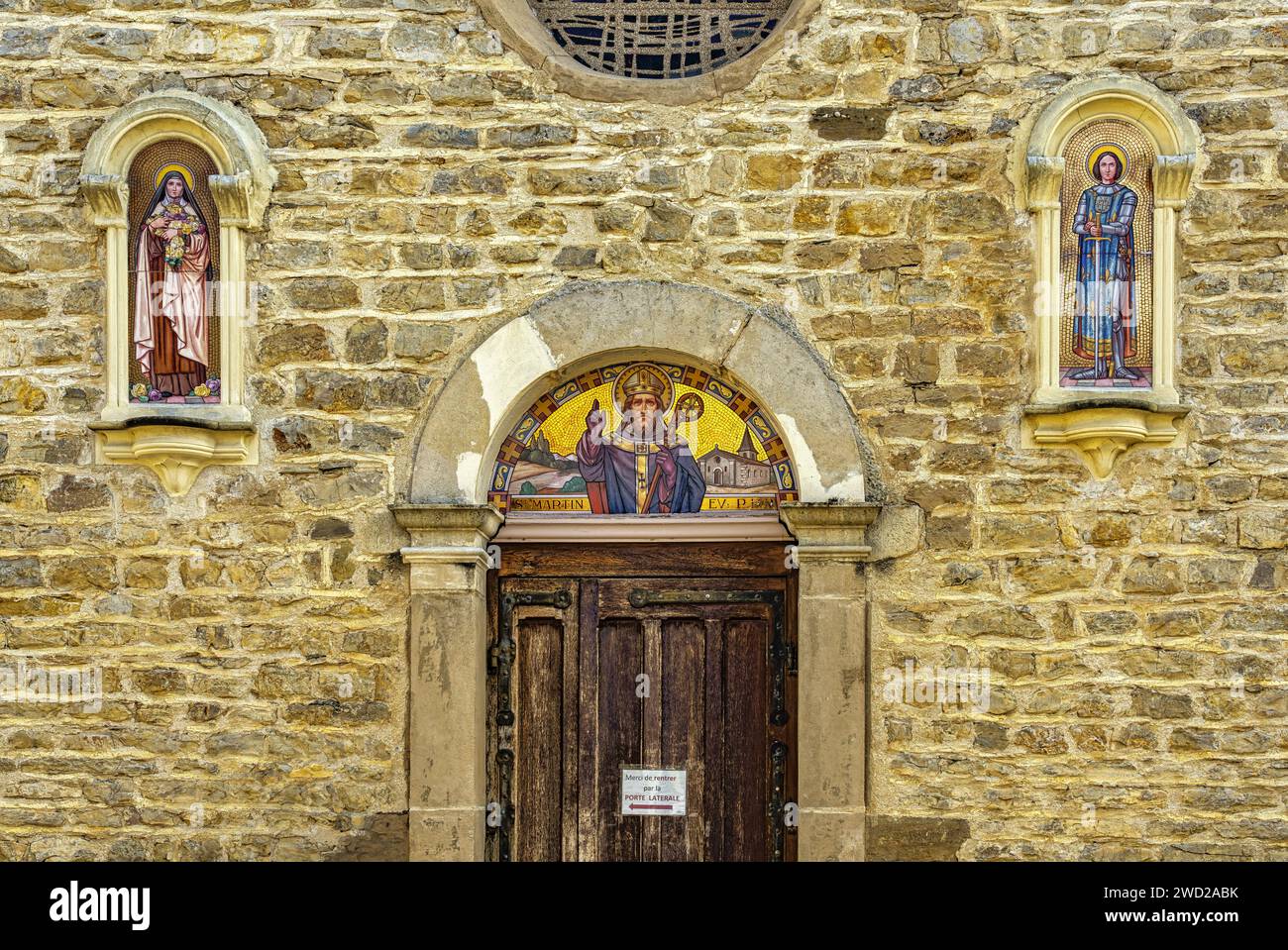 Das Tympanon des Portals der Fassade ist mit Mosaiken von St. verziert Martin, der Bischof, Jeanne von Arc und St. Therese von Lisieux. Villefontaine Stockfoto