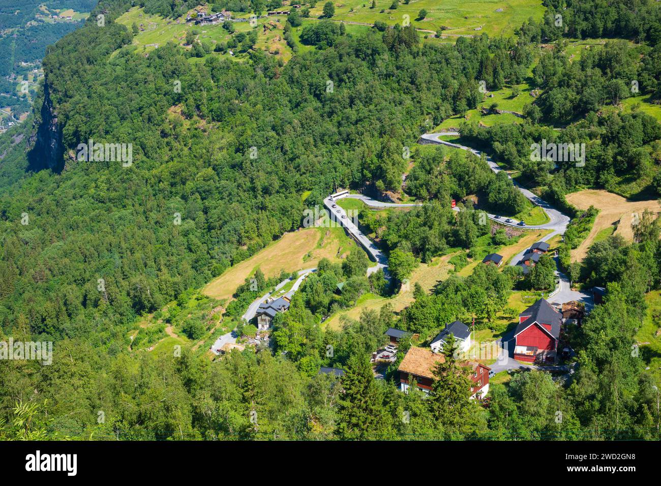 Eine malerische, gewundene Bergstraße mit einem roten, zweistöckigen Haus im beliebten Touristenziel Geiranger, Norwegen, das zum UNESCO-Weltkulturerbe gehört Stockfoto