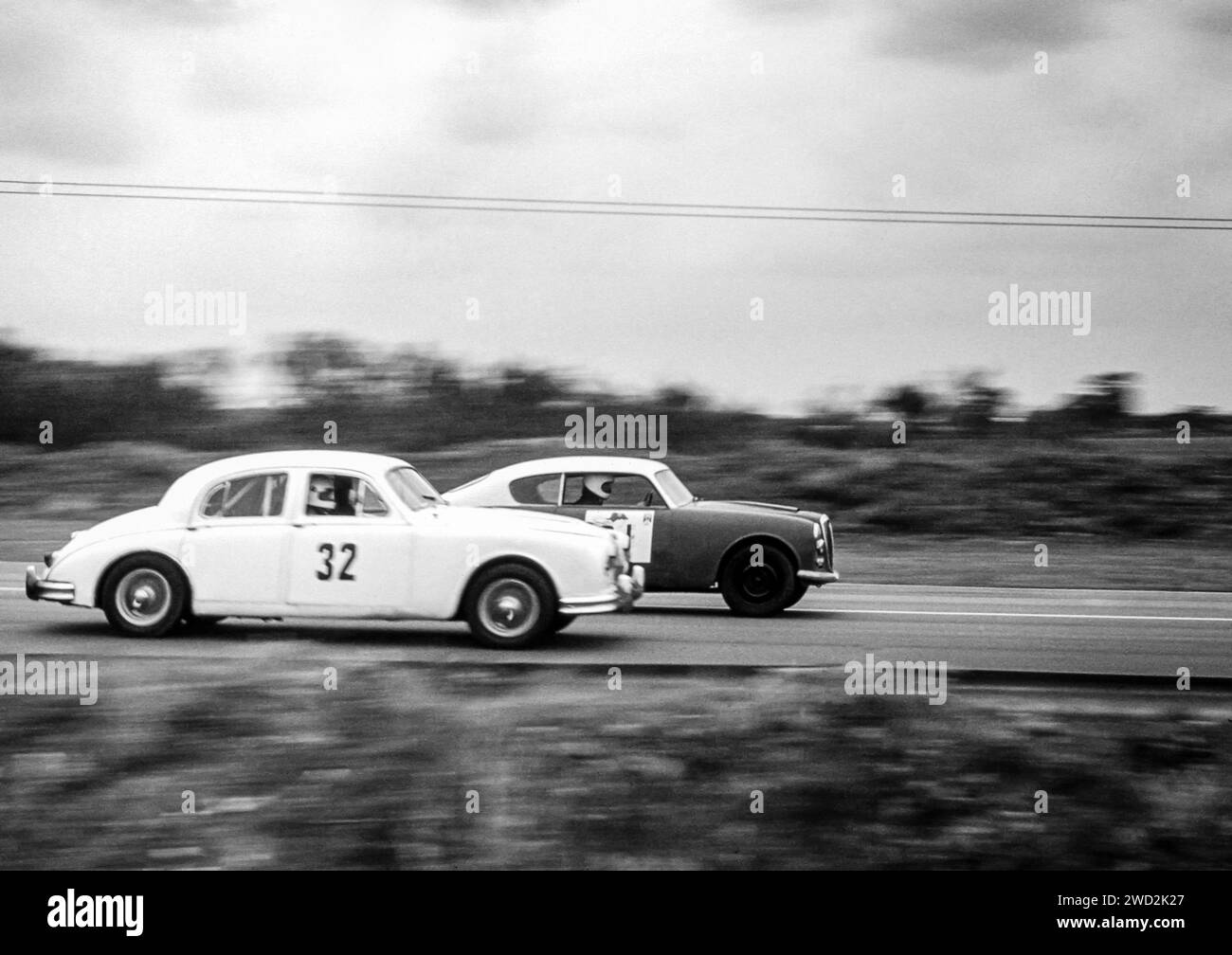 Ein Jaguar MKII Racing gegen ein Lancia Aurelia B20 Coupé in den frühen 1970er Jahren auf dem Snetterton Circuit, Race Track, Norfolk. Ursprüngliches Archivbild. Stockfoto