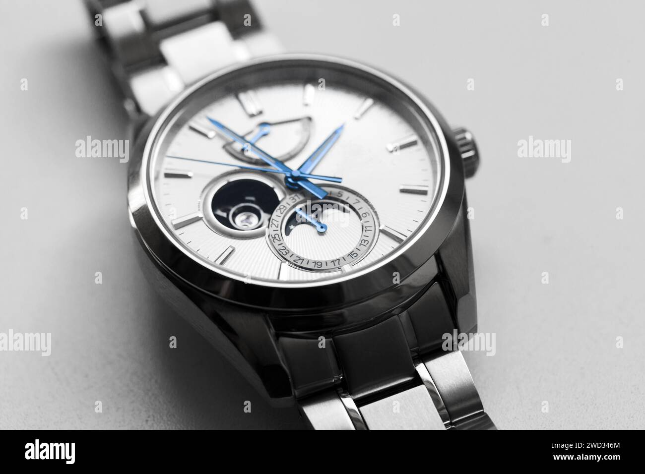 Mechanische Mondphasenarmbanduhr mit weißem Zifferblatt und blauen Zeigern, Nahaufnahme mit selektivem Fokus Stockfoto