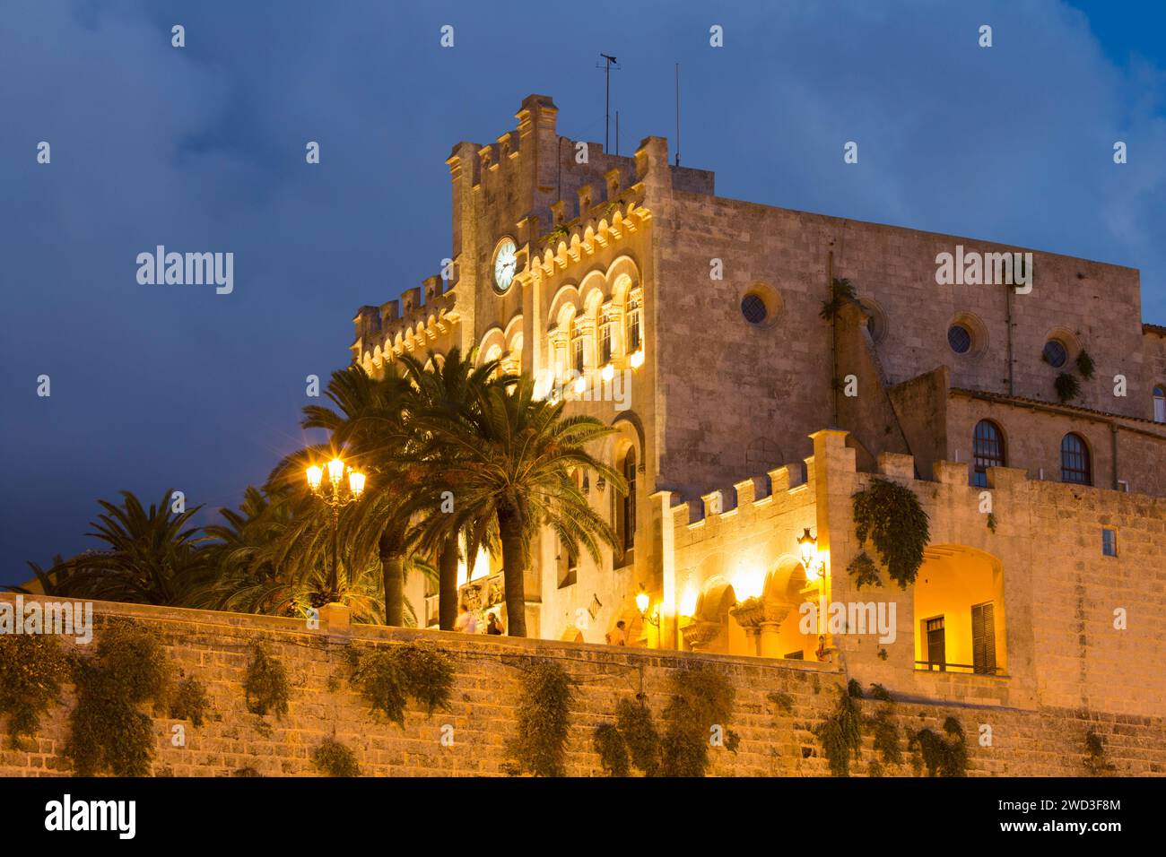 Ciutadella, Menorca, Balearen, Spanien. Flacher Blick auf das beleuchtete Rathaus aus aus dem 19. Jahrhundert auf der Plac d'es Born, Abenddämmerung. Stockfoto