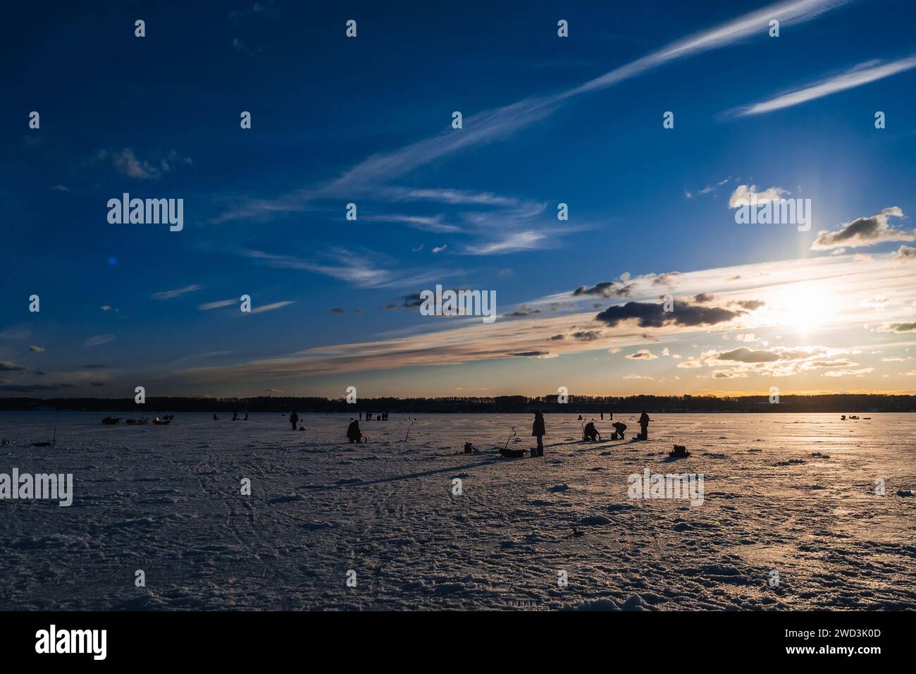 Silhouetten von Fischern und Eisschrauben im Winter auf dem See bei Sonnenaufgang am Morgen Stockfoto