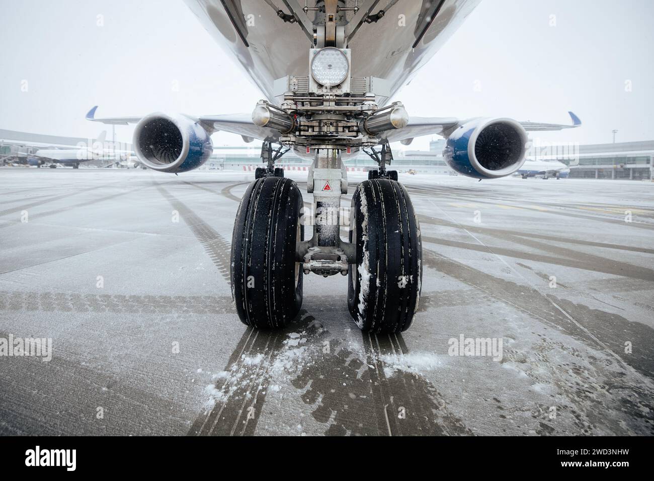 Vorderansicht des Fahrwerks des Flugzeugs. Winter frostiger Tag am Flughafen bei Schneefall. Stockfoto
