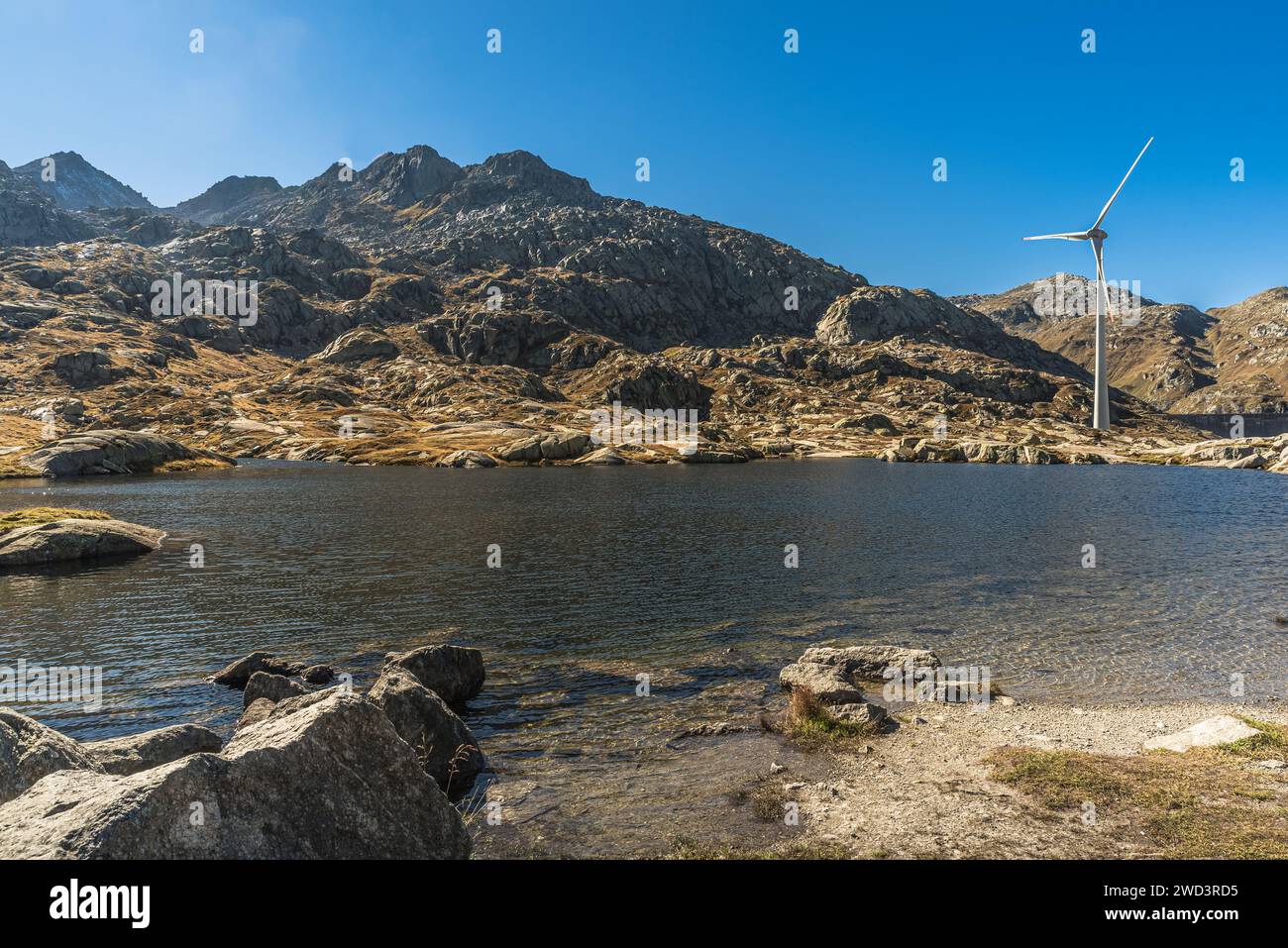 Windenergieanlage auf einem kleinen Bergsee auf der Spitze des Gotthardpasses, Kanton Tessin, Schweiz Stockfoto