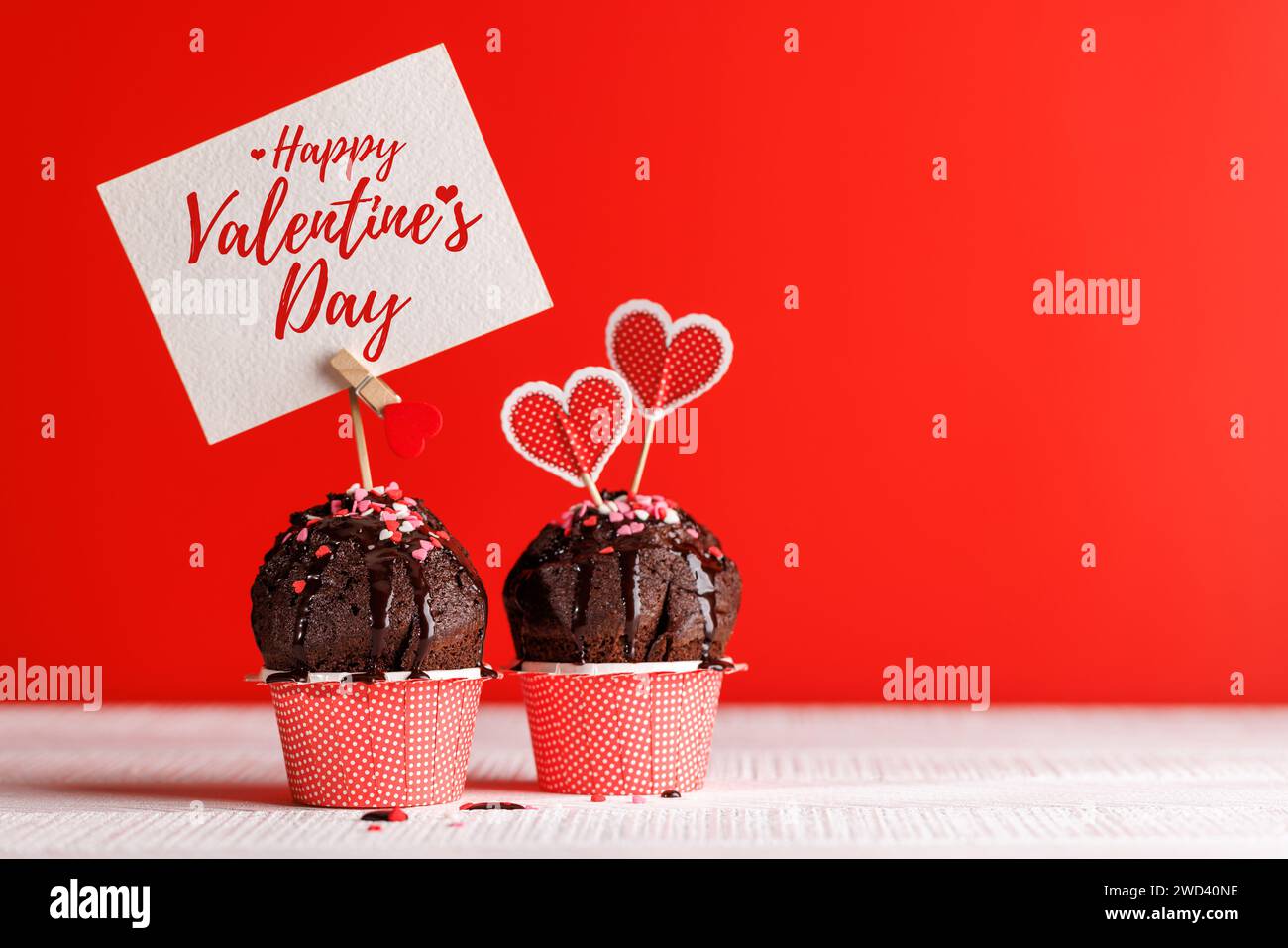 Cupcake Love: Herzhafte Leckereien vor leuchtendem rotem Hintergrund mit Kopierraum für Ihre Valentinstag-Grüße Stockfoto