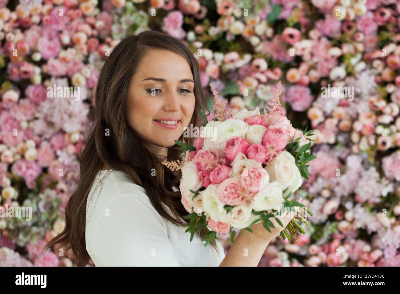 Schöne gesunde Frau lächelt und hält bunte rosa Farbe Blumenstrauß auf floralem Frühling oder Sommer Hintergrund, Studio Mode Schönheit Porträt Stockfoto